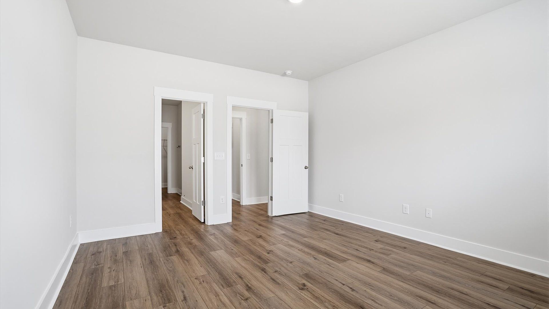 Serene and stylish primary bedroom featuring hardwood flooring and a thoughtful, modern layout near Downtown Anderson