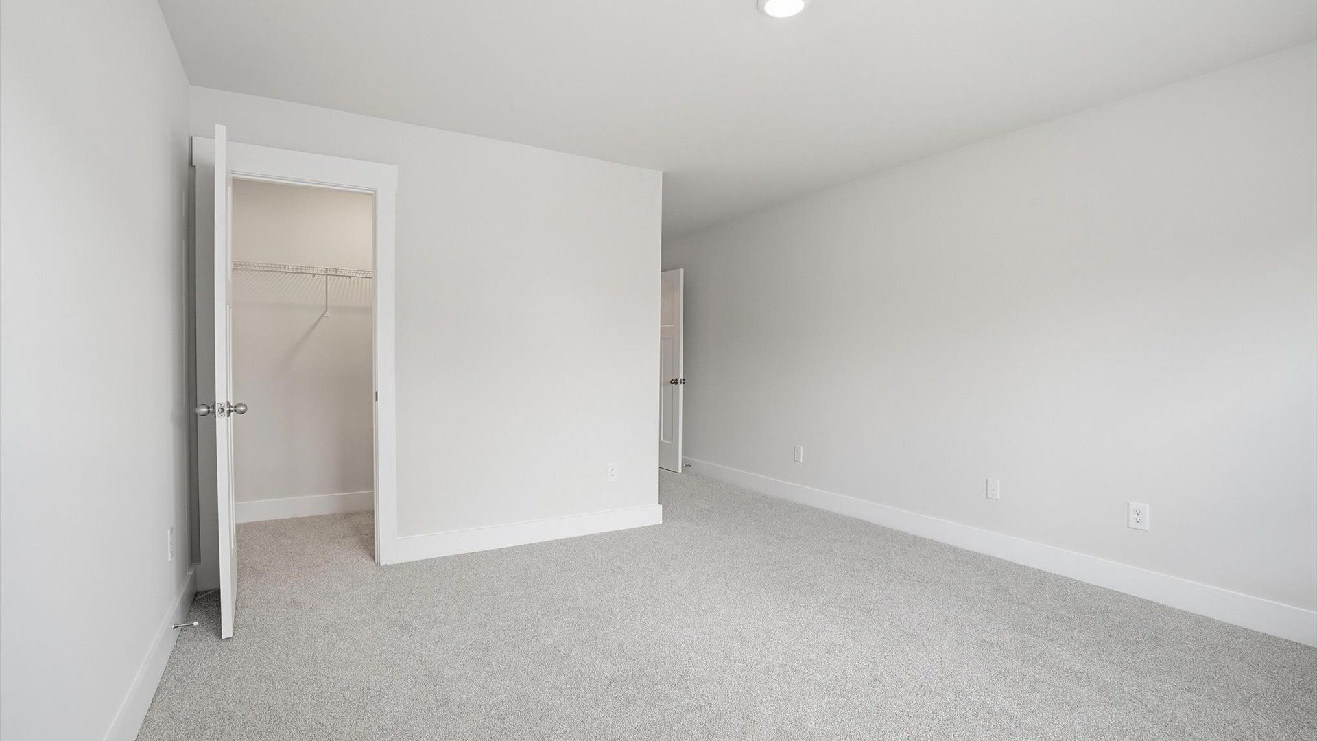 First-rate secondary bedroom with a spacious walk-in closet and elegant carpeted flooring at Village at Midway
