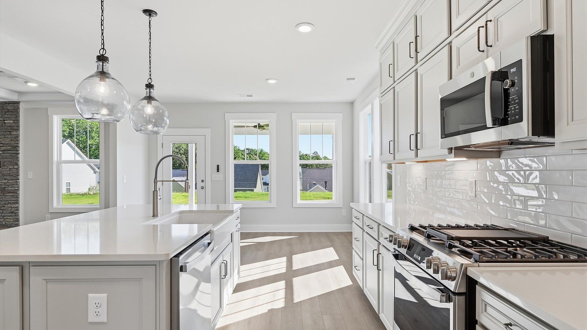 Tasteful design meets functional luxury in this kitchen with a 9-foot island and modern pendant lighting by DRB Homes