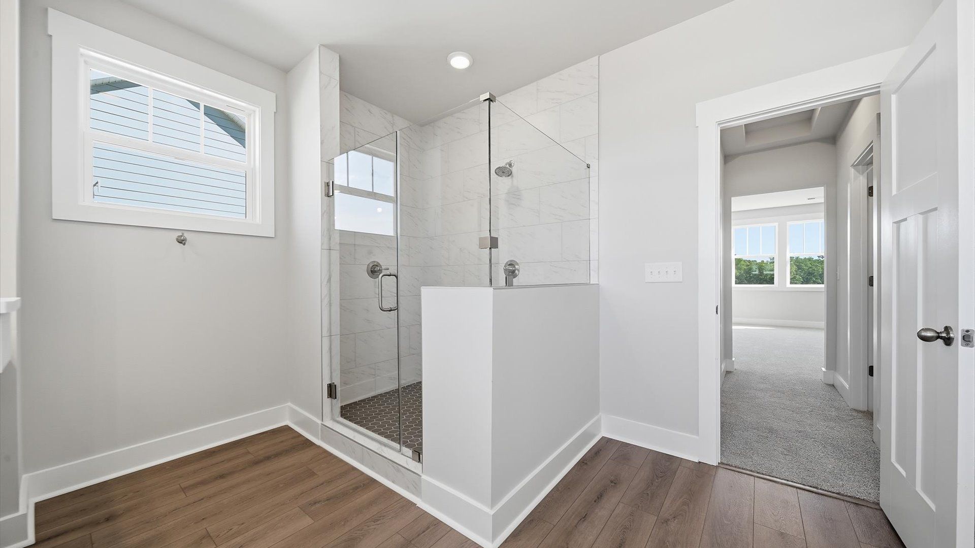 Spacious and modern primary bathroom with walk-in shower and abundant natural light by DRB Homes