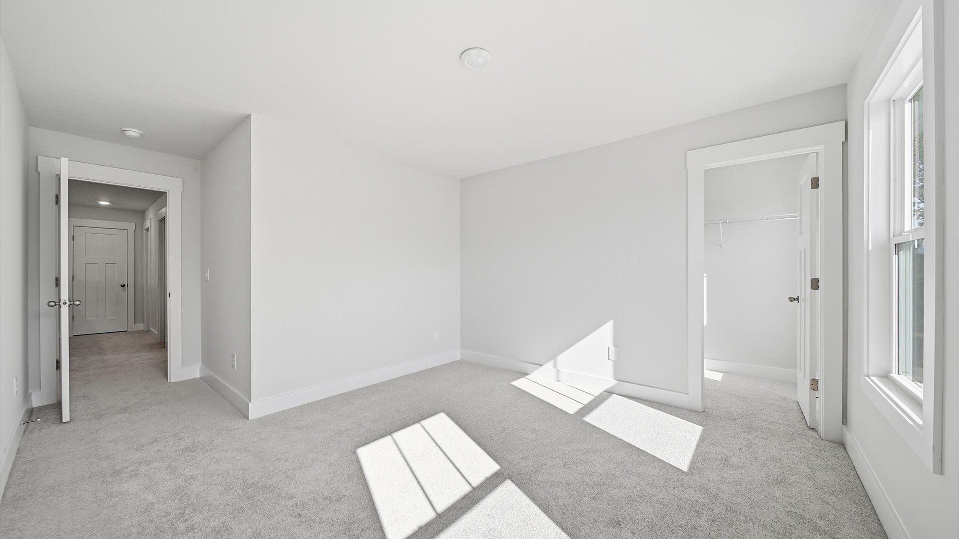 Superior comfort in this light-filled bedroom with plush carpeting and thoughtfully placed large windows at Creeks at Midway