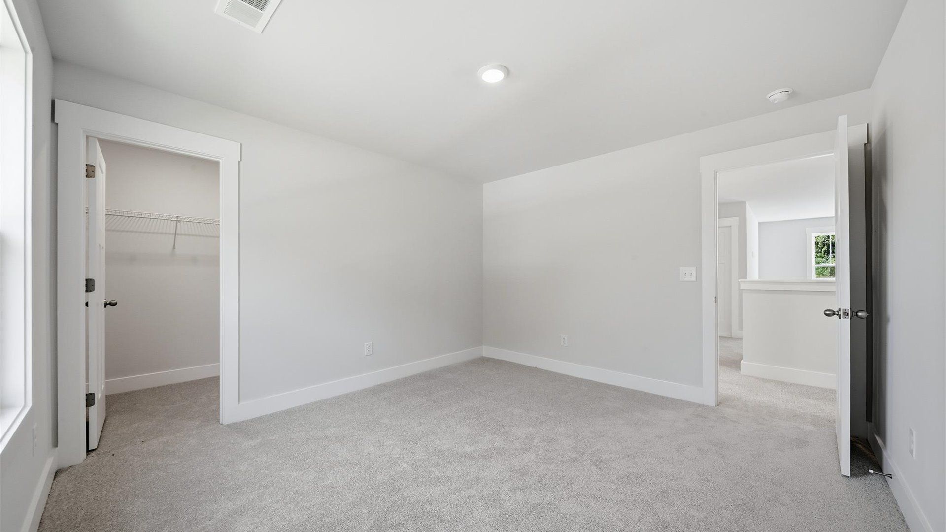 Notable secondary bedroom offering cozy carpeted flooring and a stylish walk-in closet