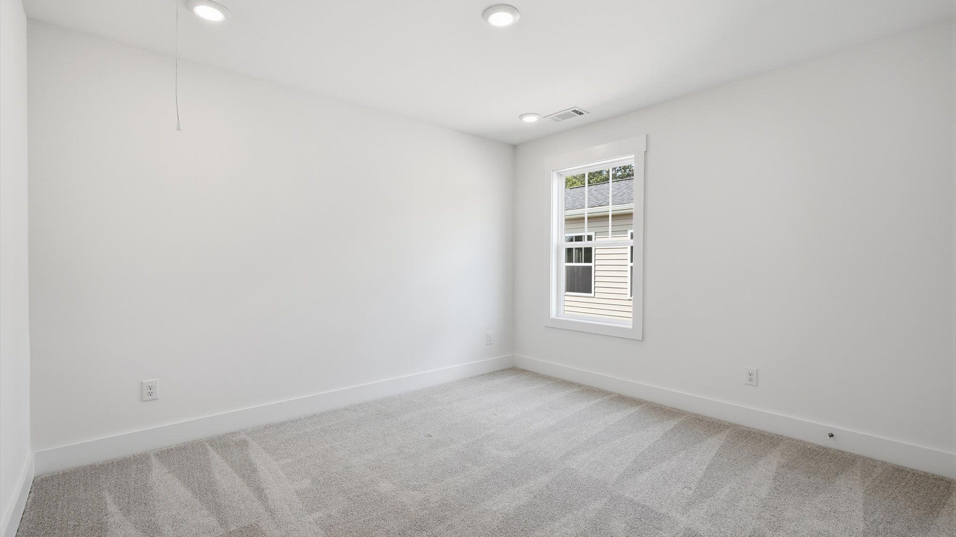 Accomplished design in this restful bedroom featuring plush carpet and oversized window views at Iris Meadows