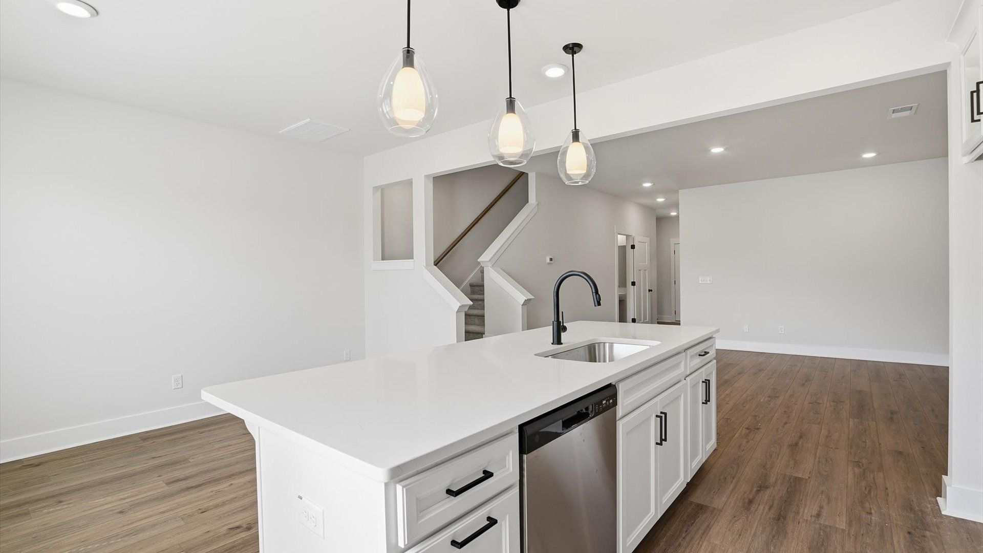 Tasteful design meets functional luxury in this kitchen with a center island and modern pendant lighting by DRB Homes