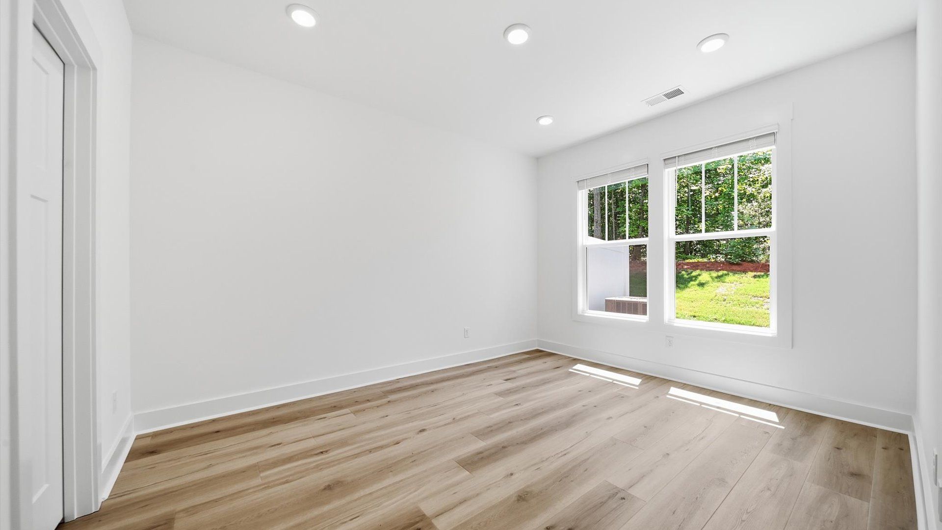 Serene and stylish main-level primary bedroom featuring hardwood flooring and a thoughtful, modern layout