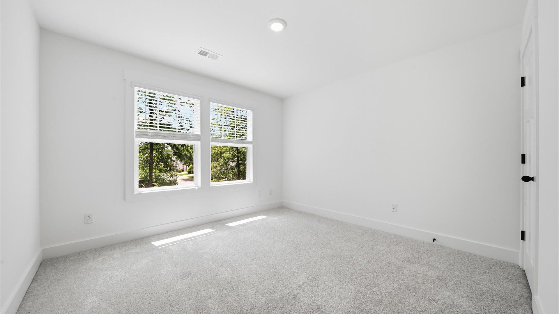 Elegant bedroom retreat featuring soft carpet and oversized windows that create a bright, welcoming space