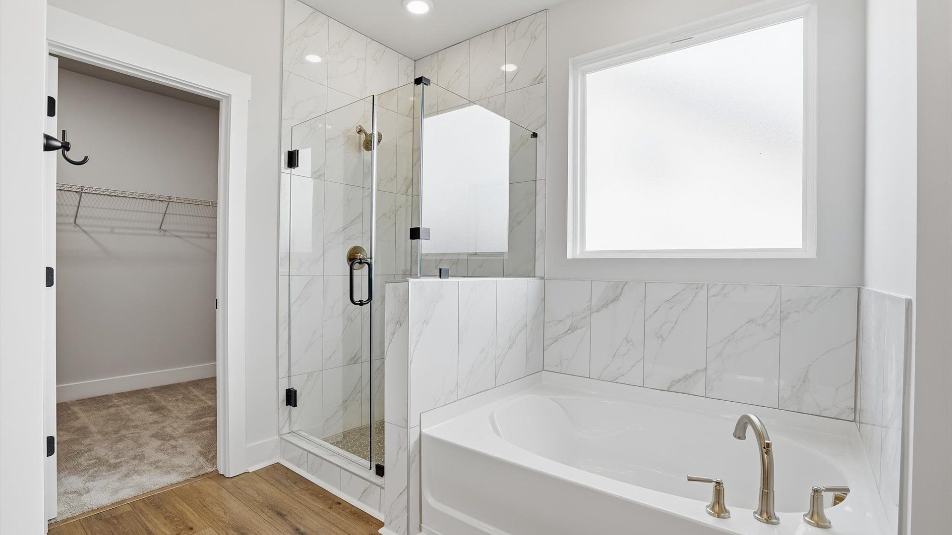 Superior en-suite primary bathroom with natural light and a large soaking tub—crafted with high standards in mind