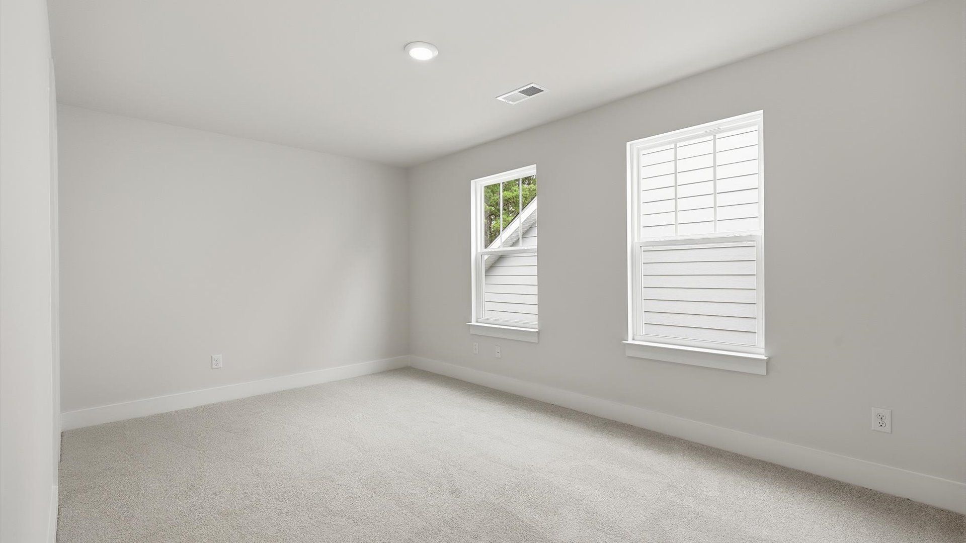 Highly functional bedroom with large windows, carpeted flooring, and tasteful finishes throughout by DRB Homes