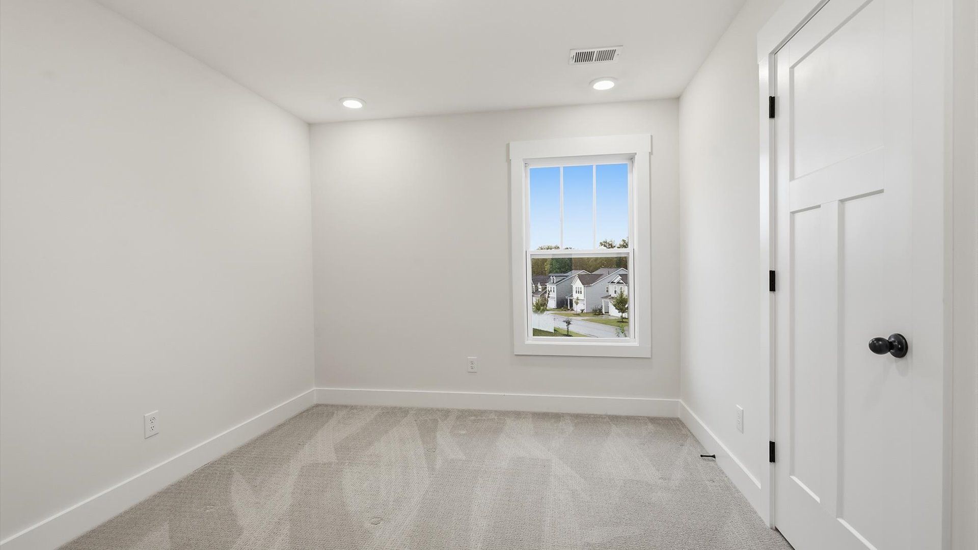 Bright and serene bedroom with comfortable carpeted flooring and a large window for vibrant light