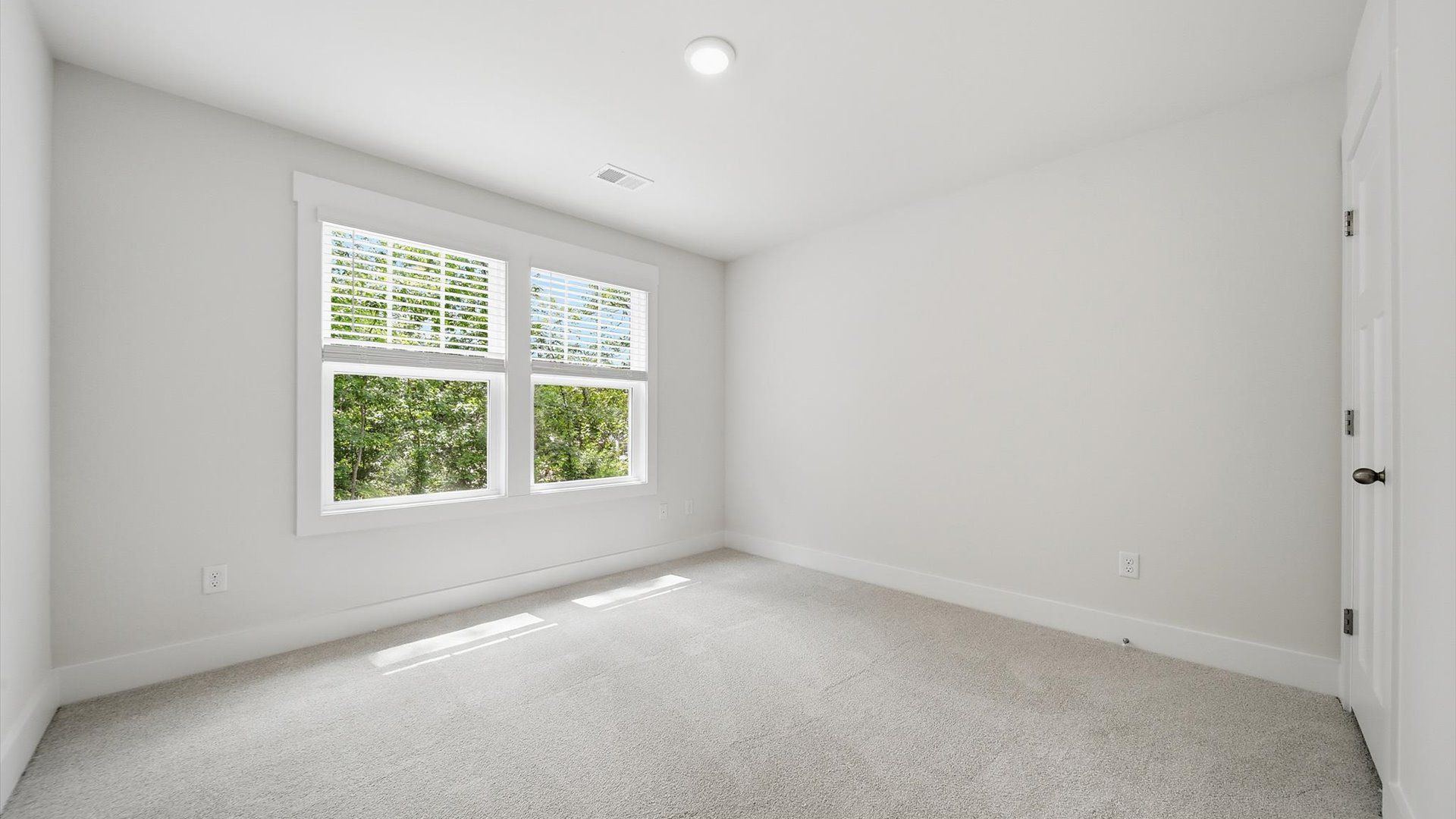 Elegant bedroom retreat featuring soft carpet and oversized windows that create a bright, welcoming space