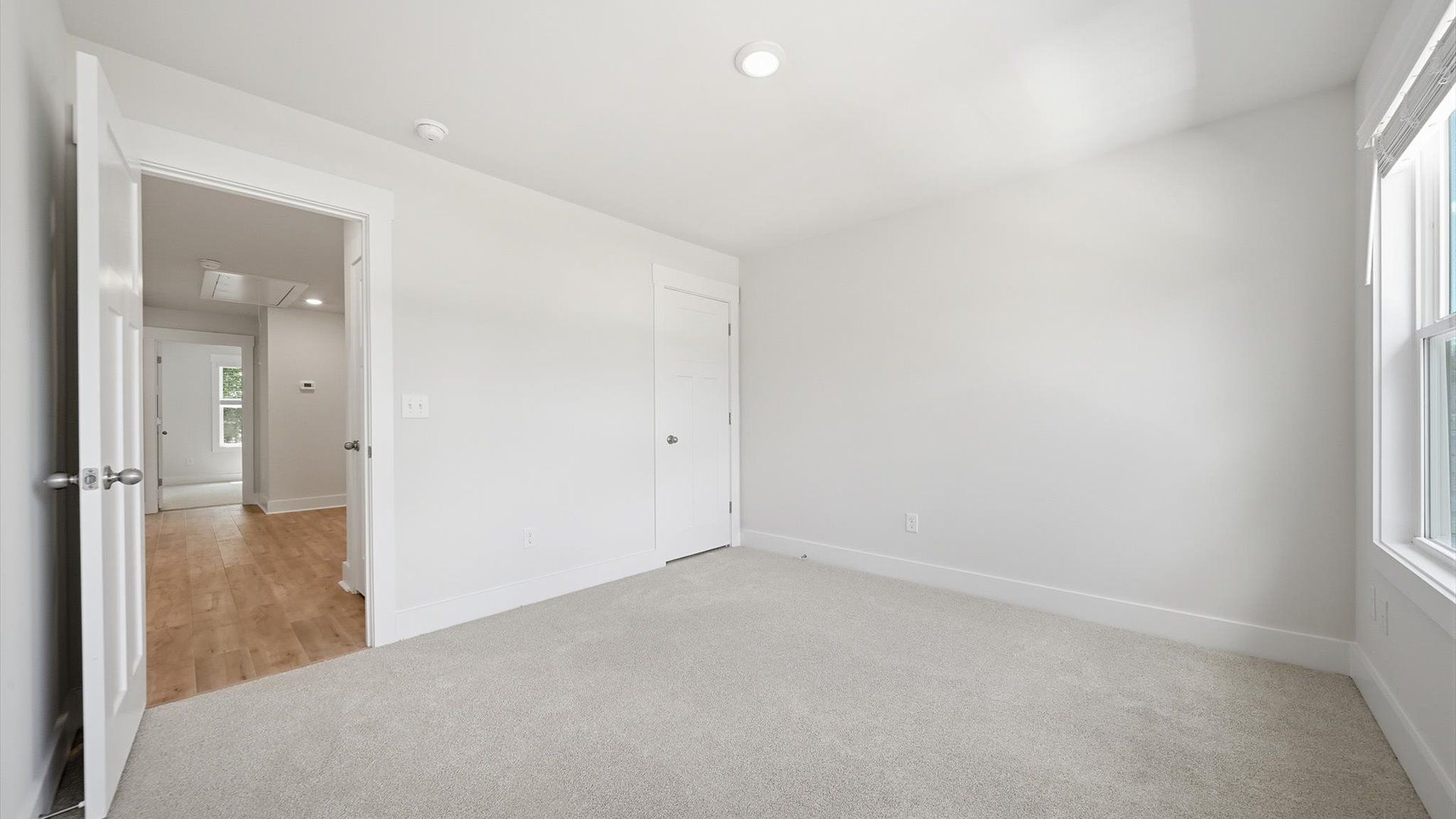 Highly functional bedroom with large windows, carpeted flooring, and tasteful finishes throughout
