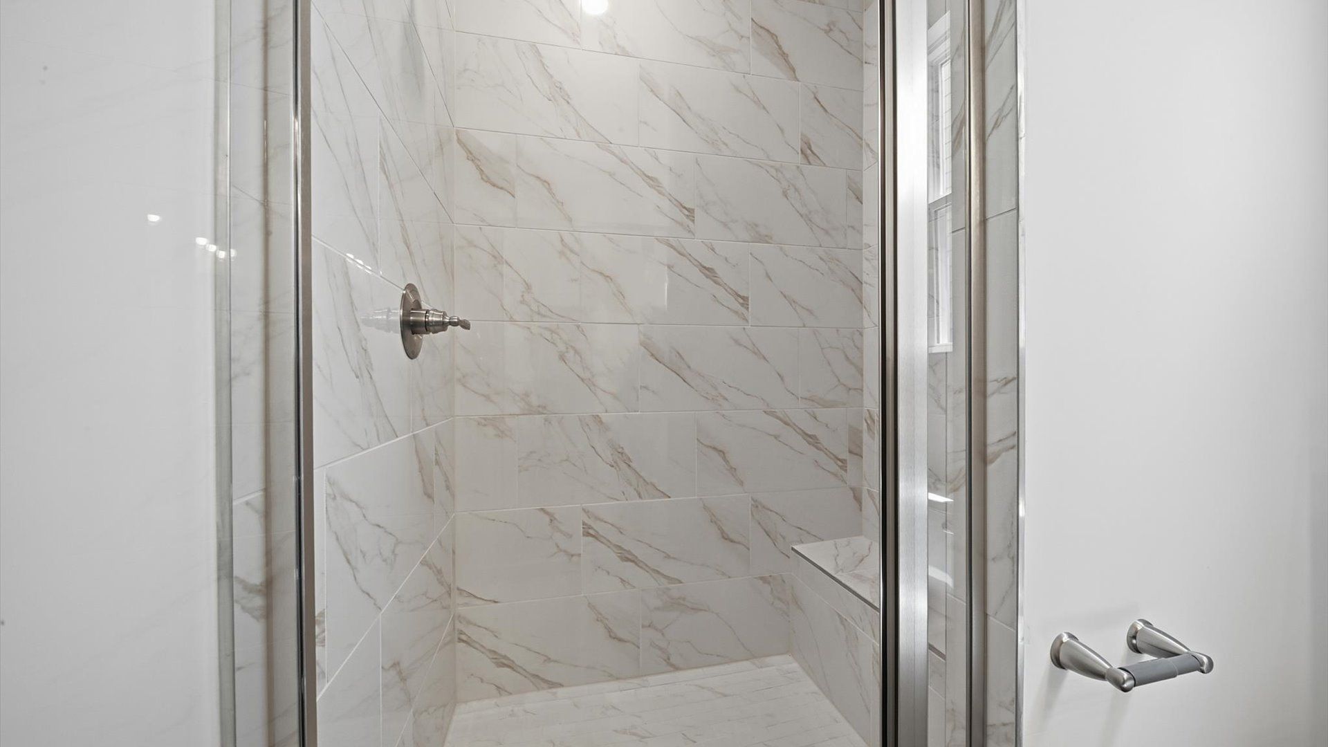 Spacious and modern primary bathroom with tiled walk-in shower and first-class double vanity setup