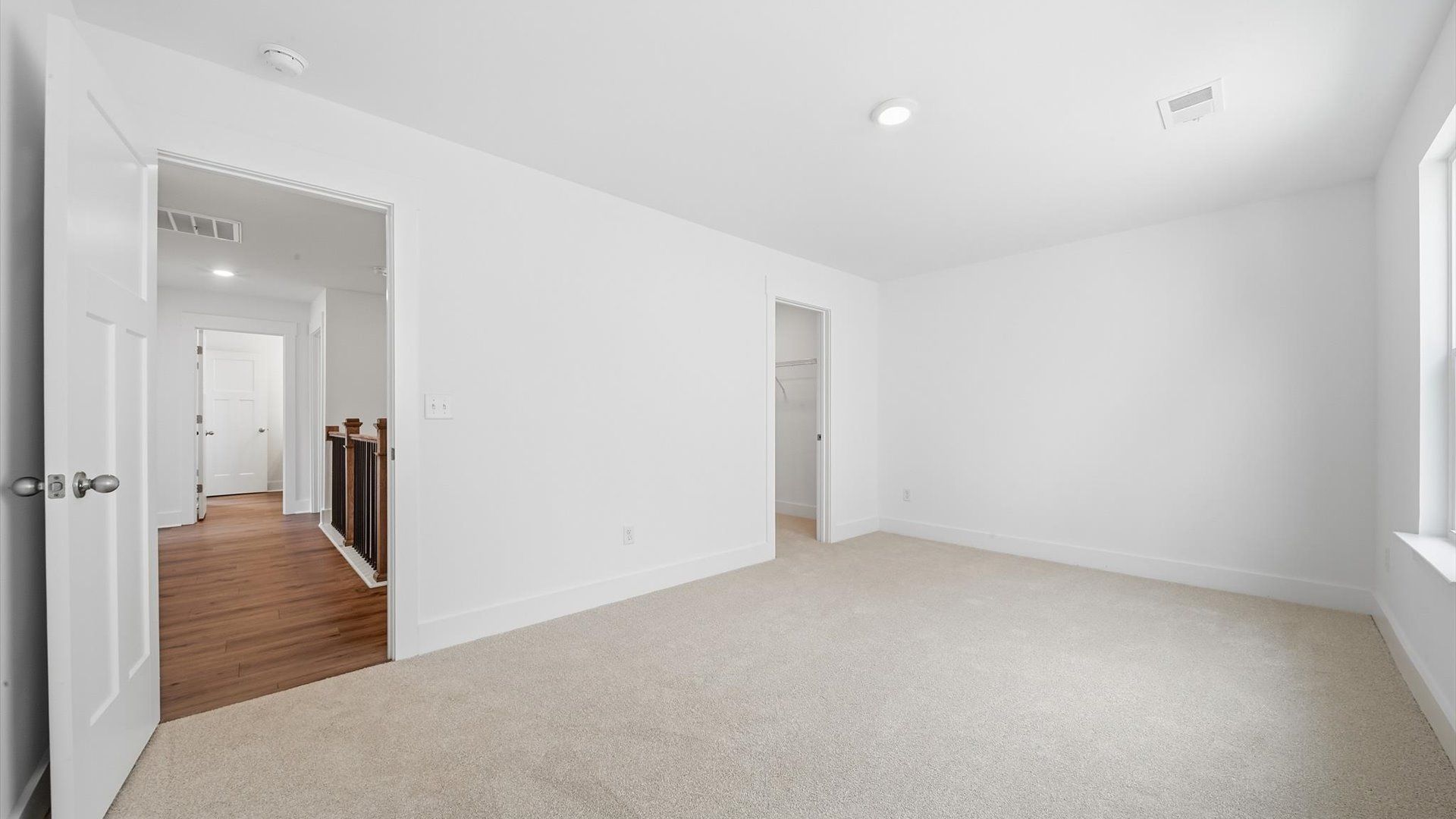 Elegant bedroom retreat featuring soft carpet and oversized windows that create a bright, welcoming space
