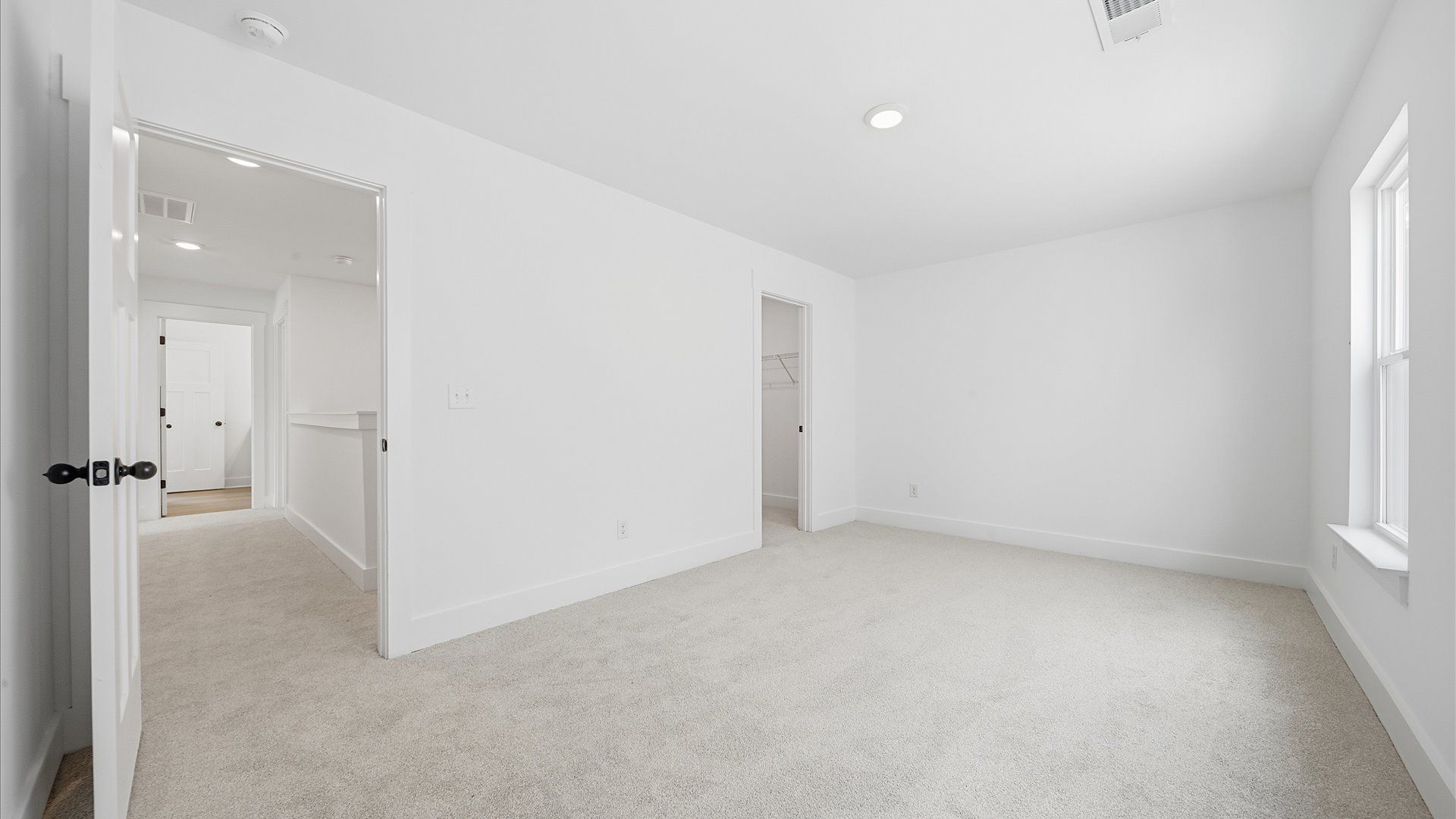 Elegant bedroom retreat featuring soft carpet and oversized windows that create a bright, welcoming space
