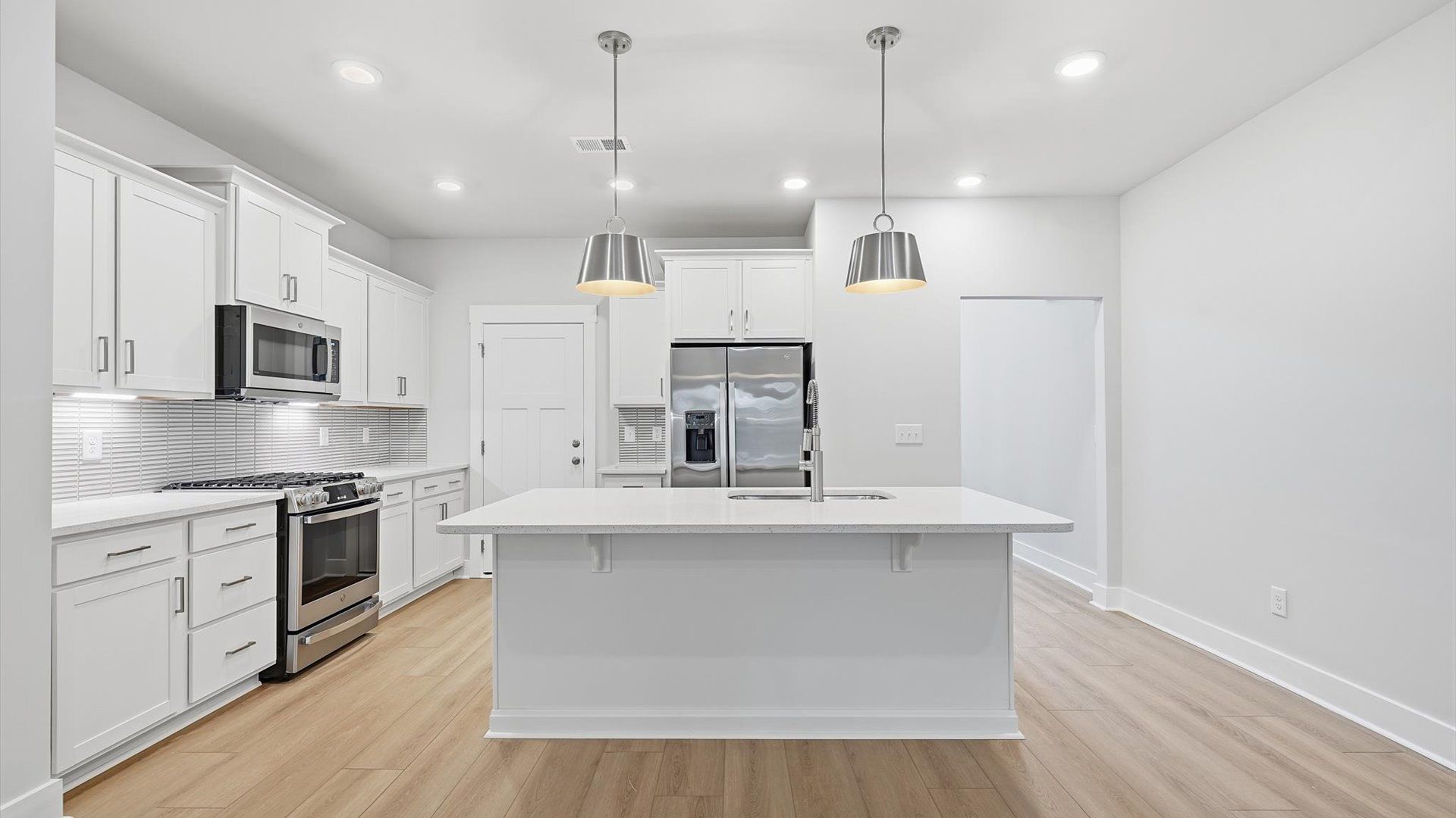 Tasteful kitchen with oversized island and stylish pendant lighting—crafted to high standards