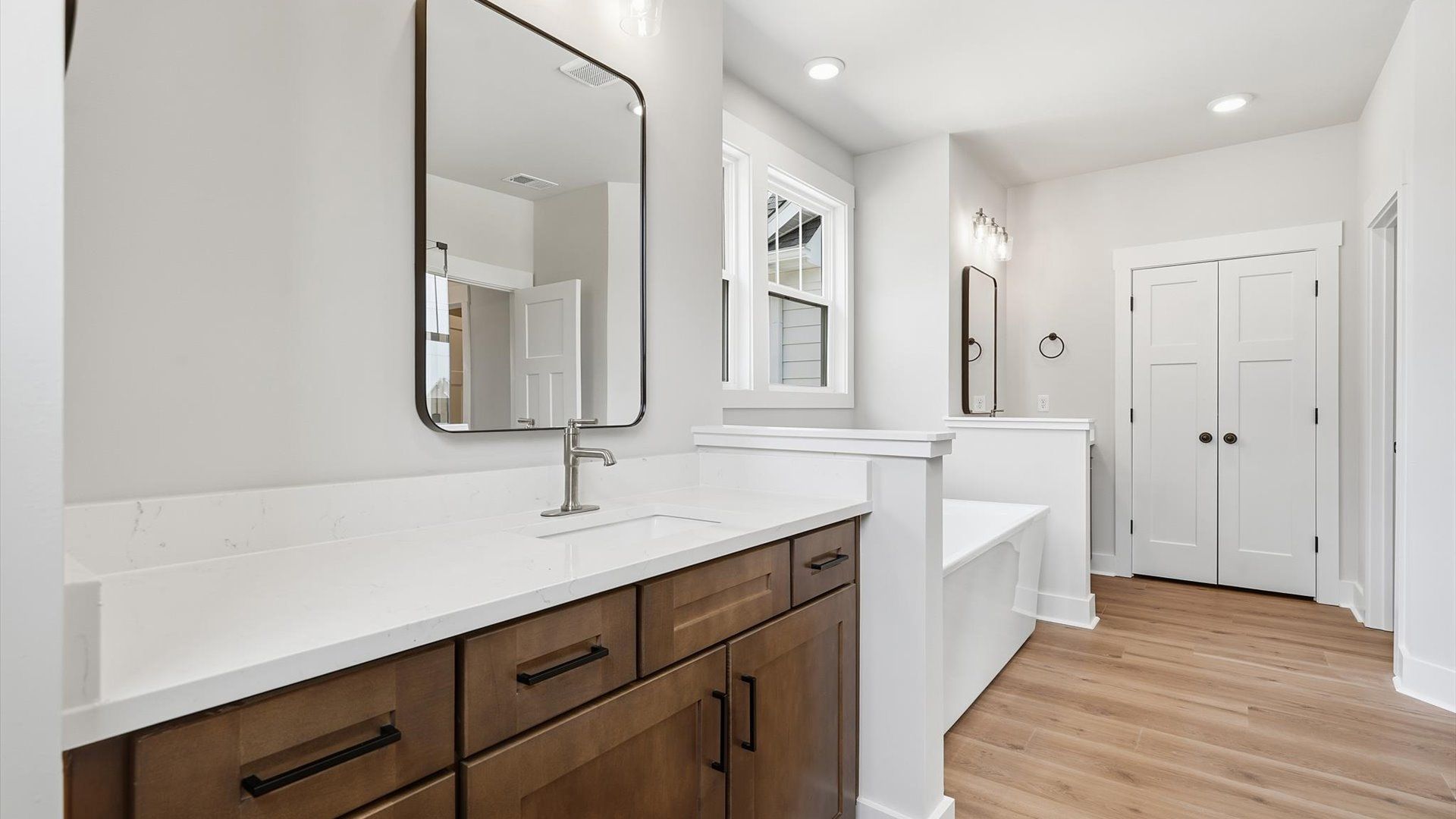 Accomplished design shines in this primary bath with separate vanities, a sleek soaking tub, and tiled walk-in shower
