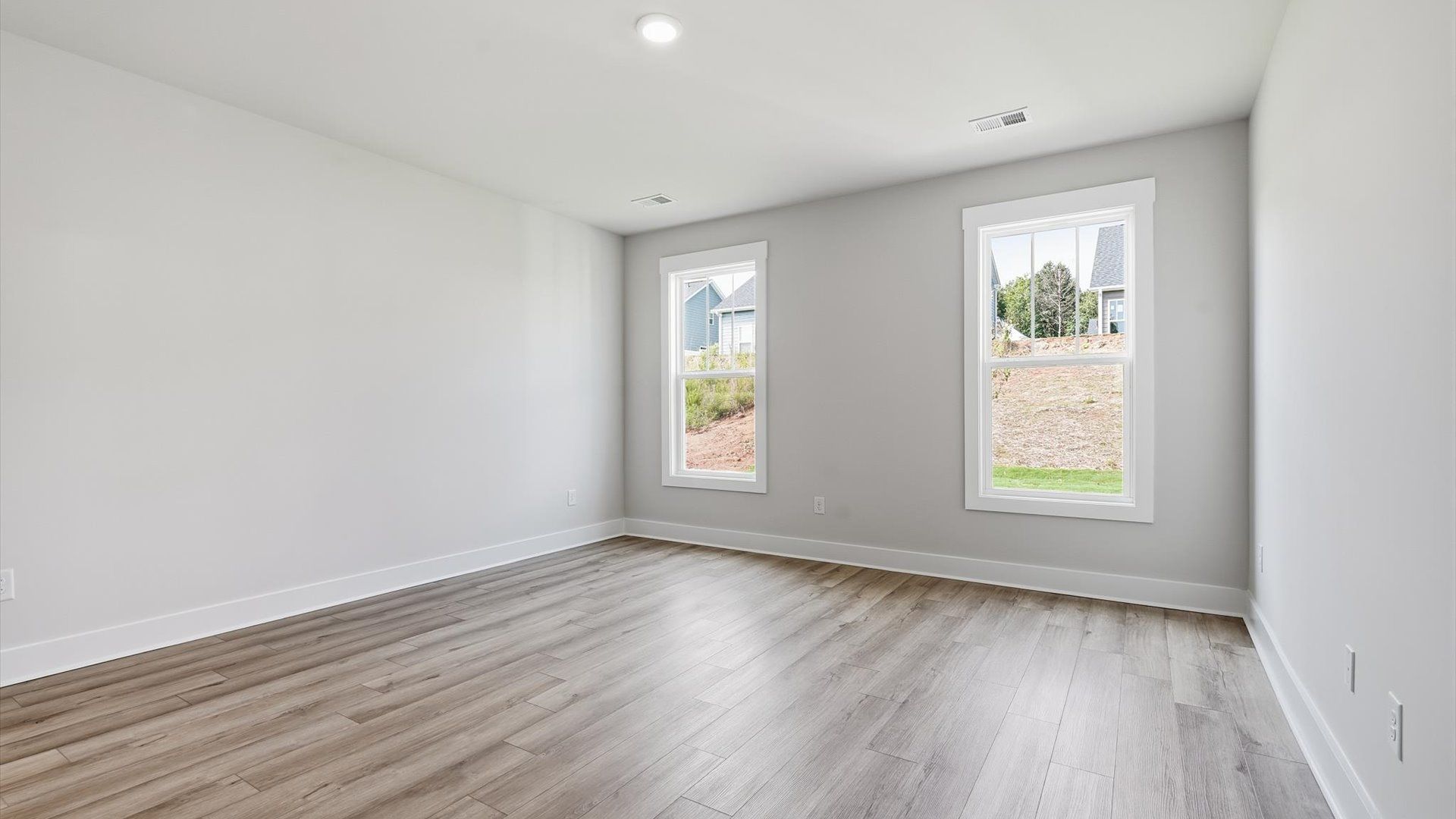 Serene and stylish primary bedroom featuring hardwood flooring and a thoughtful, modern layout