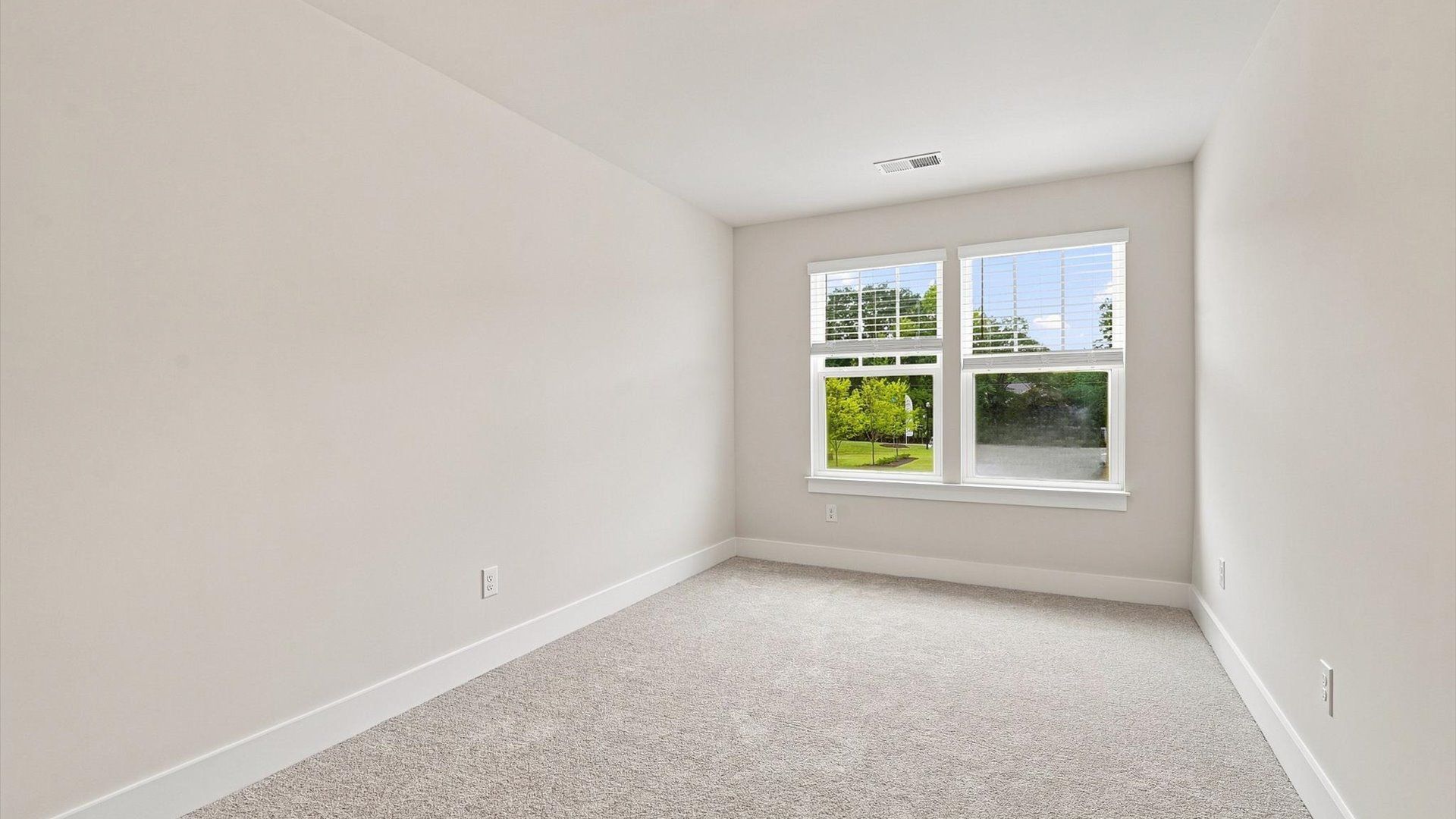 Bright and serene bedroom with comfortable carpeted flooring and large windows for vibrant light