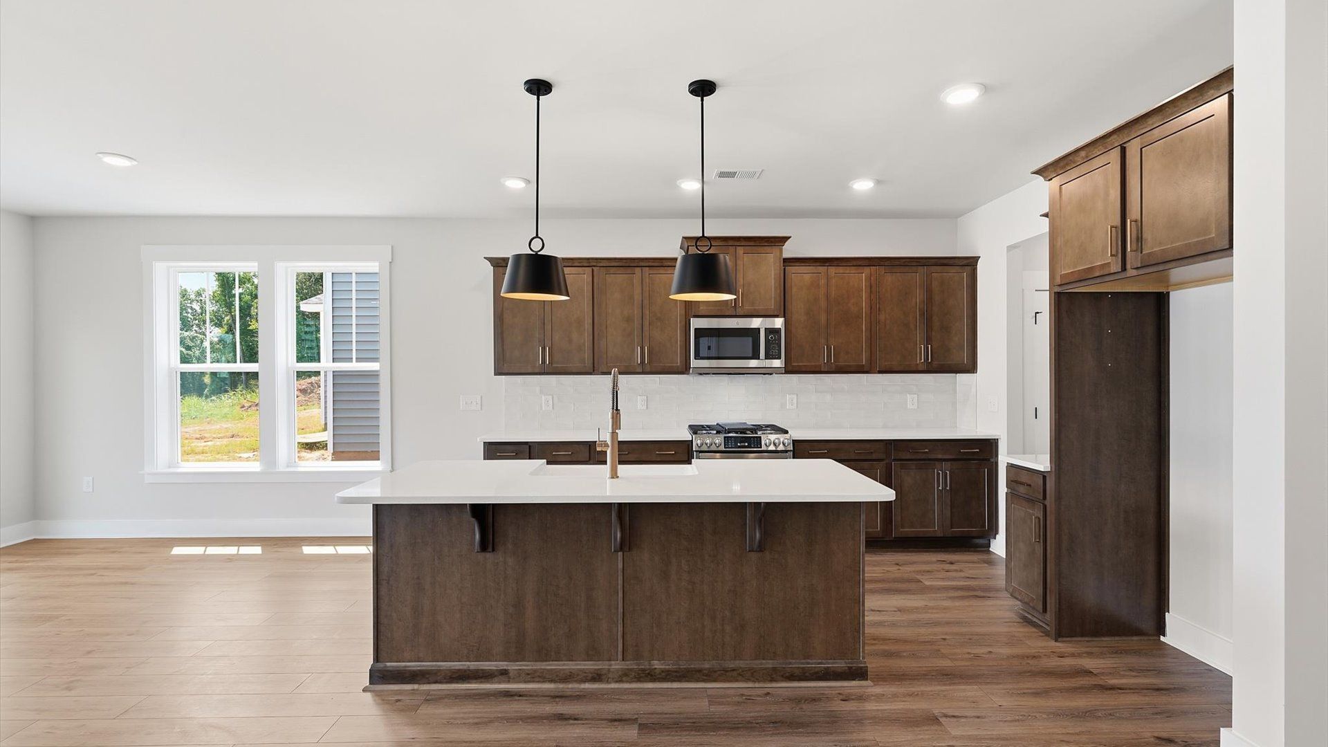 Exceptional kitchen featuring a spacious island, eye-catching pendant lights, and modern finishes by DRB Homes