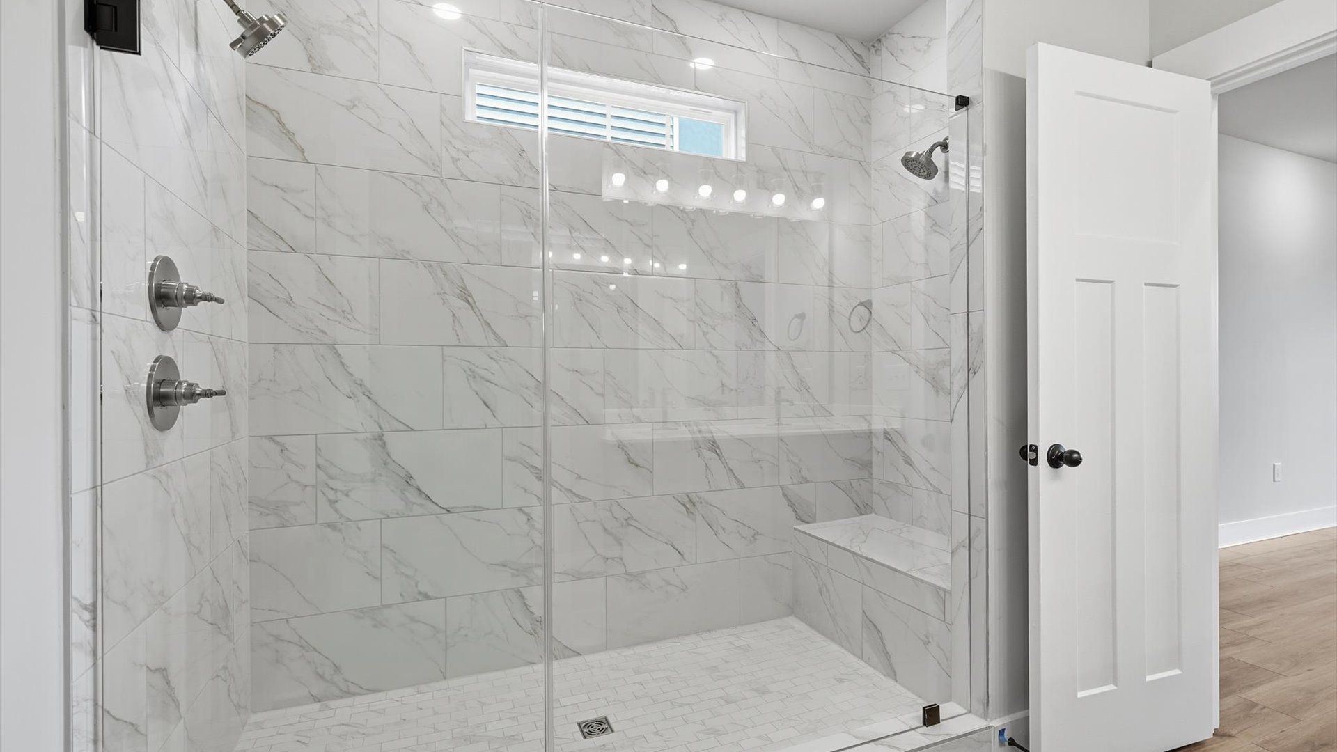Accomplished design shines in this primary bath with dual vanity and a sleek walk-in shower at Harrier Point