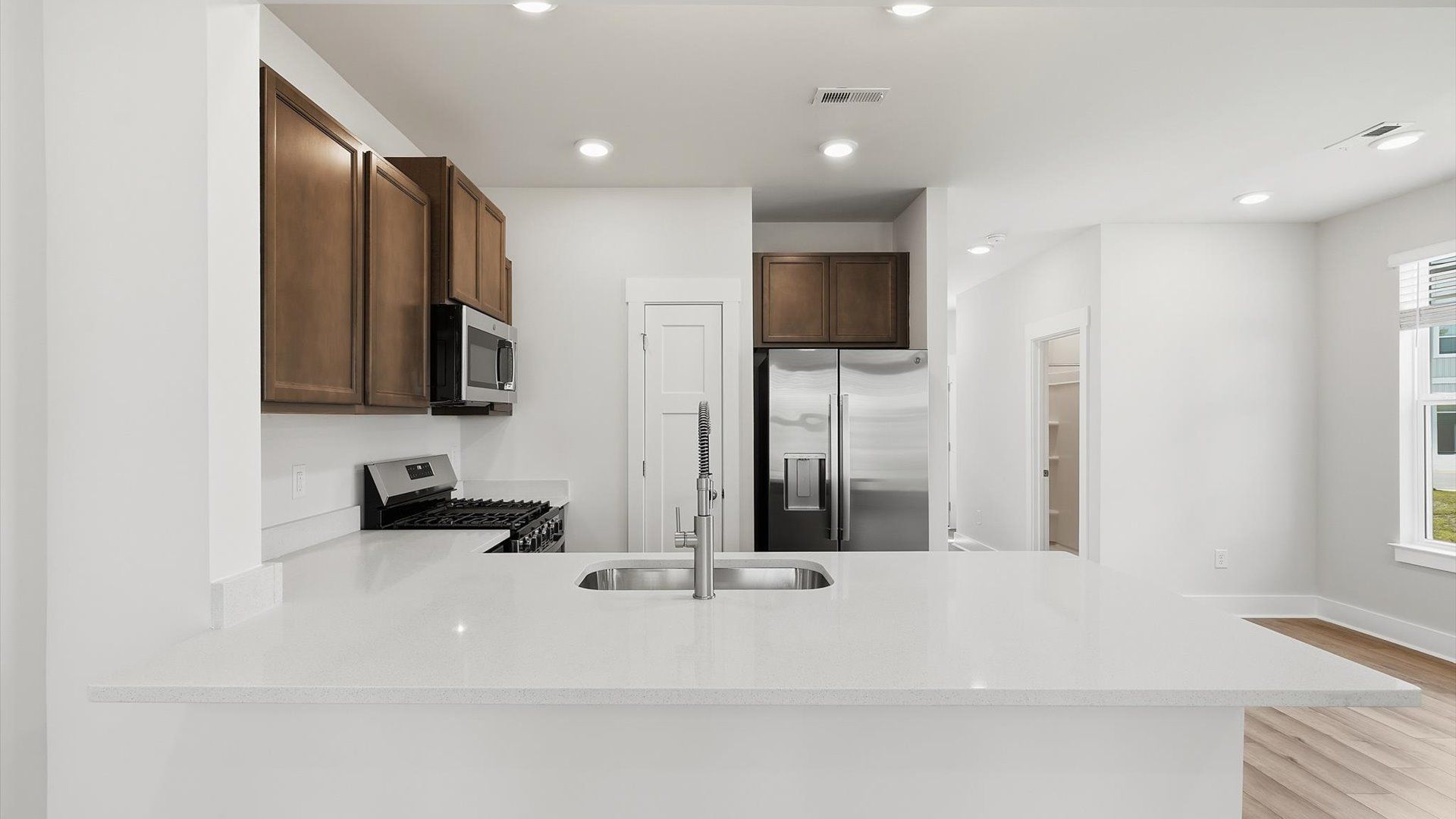 Superior kitchen with quartz countertops, natural light, and a generously sized island by DRB Homes