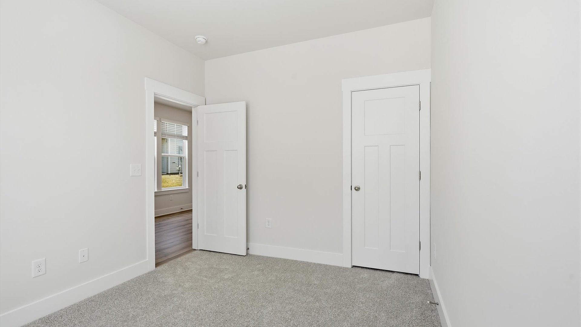 Tasteful secondary bedroom with plush carpet and a spacious walk-in closet at the Clarke Townes community