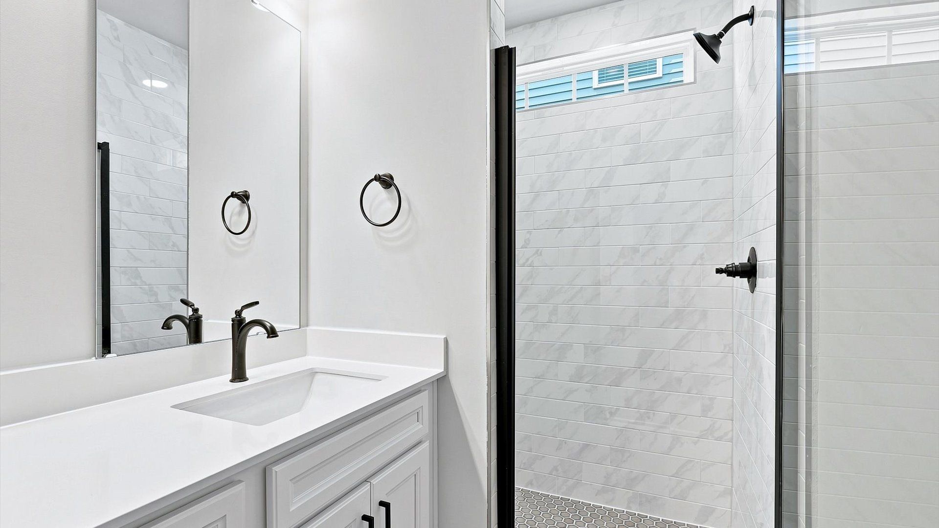 Accomplished design shines in this primary bath with dual vanity and a sleek tiled walk-in shower