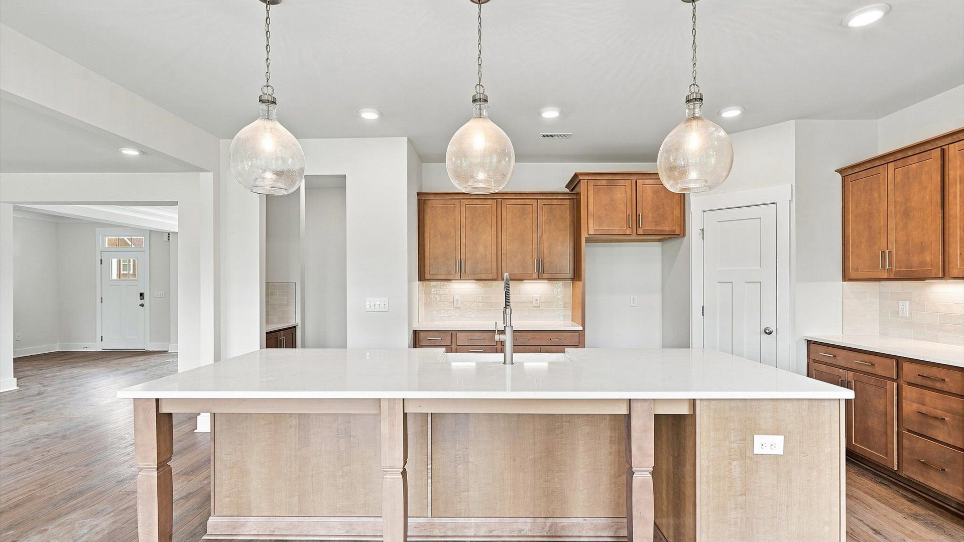 Highly skilled kitchen design includes a 10-foot island, quartz countertops, and stylish pendant fixtures