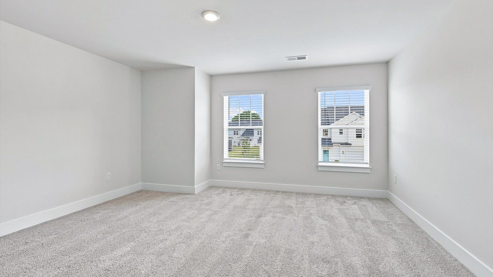 Notable bedroom offering soft carpet, a walk-in closet, and expansive windows overlooking the yard at Village at Midway