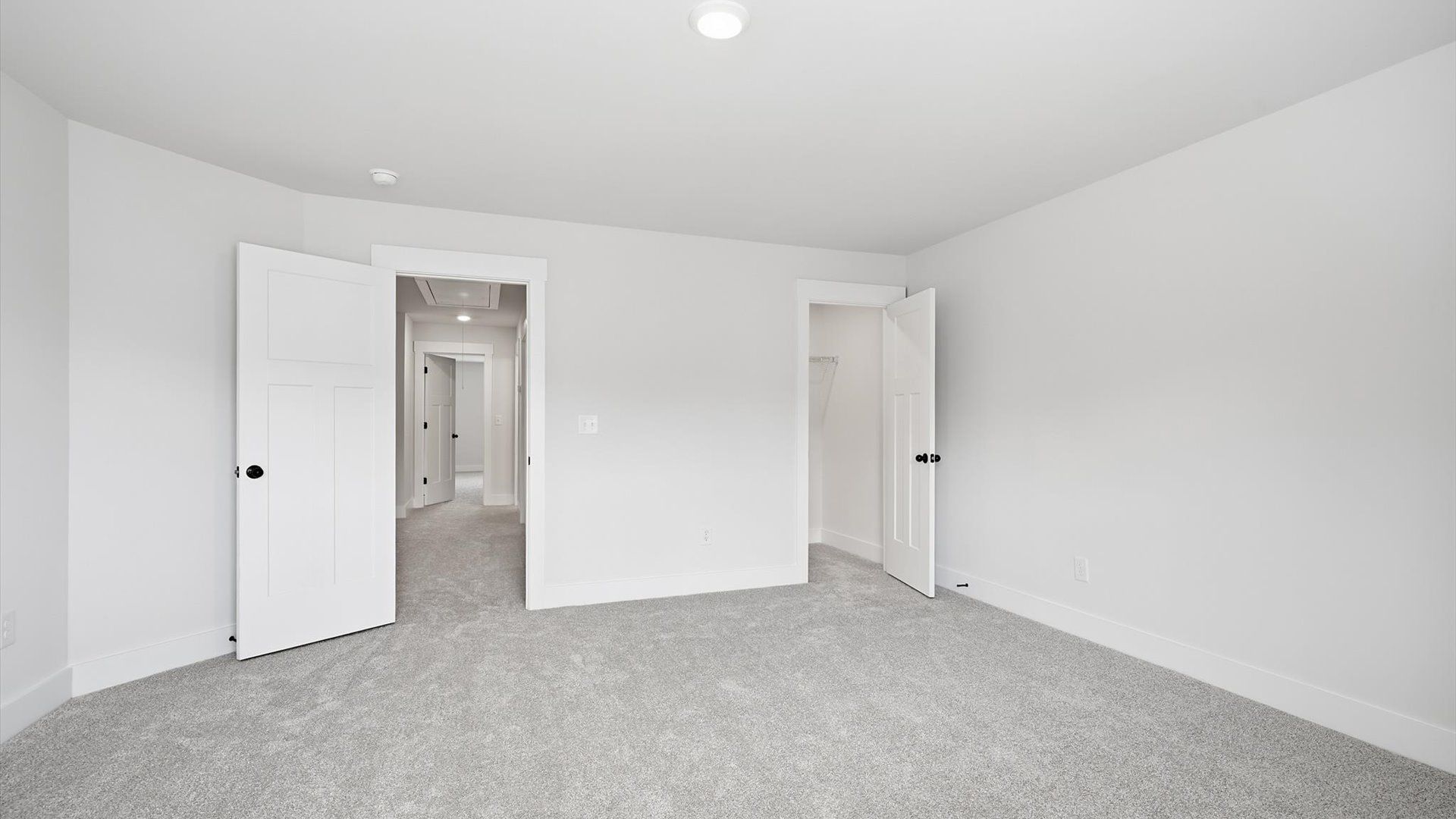 Elegant bedroom retreat featuring soft carpeting and a thoughtfully designed walk-in closet at Village at Midway