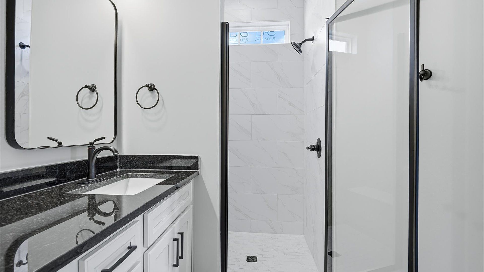 Tasteful primary bath with modern finishes, a tiled walk-in shower, and thoughtful double vanity layout