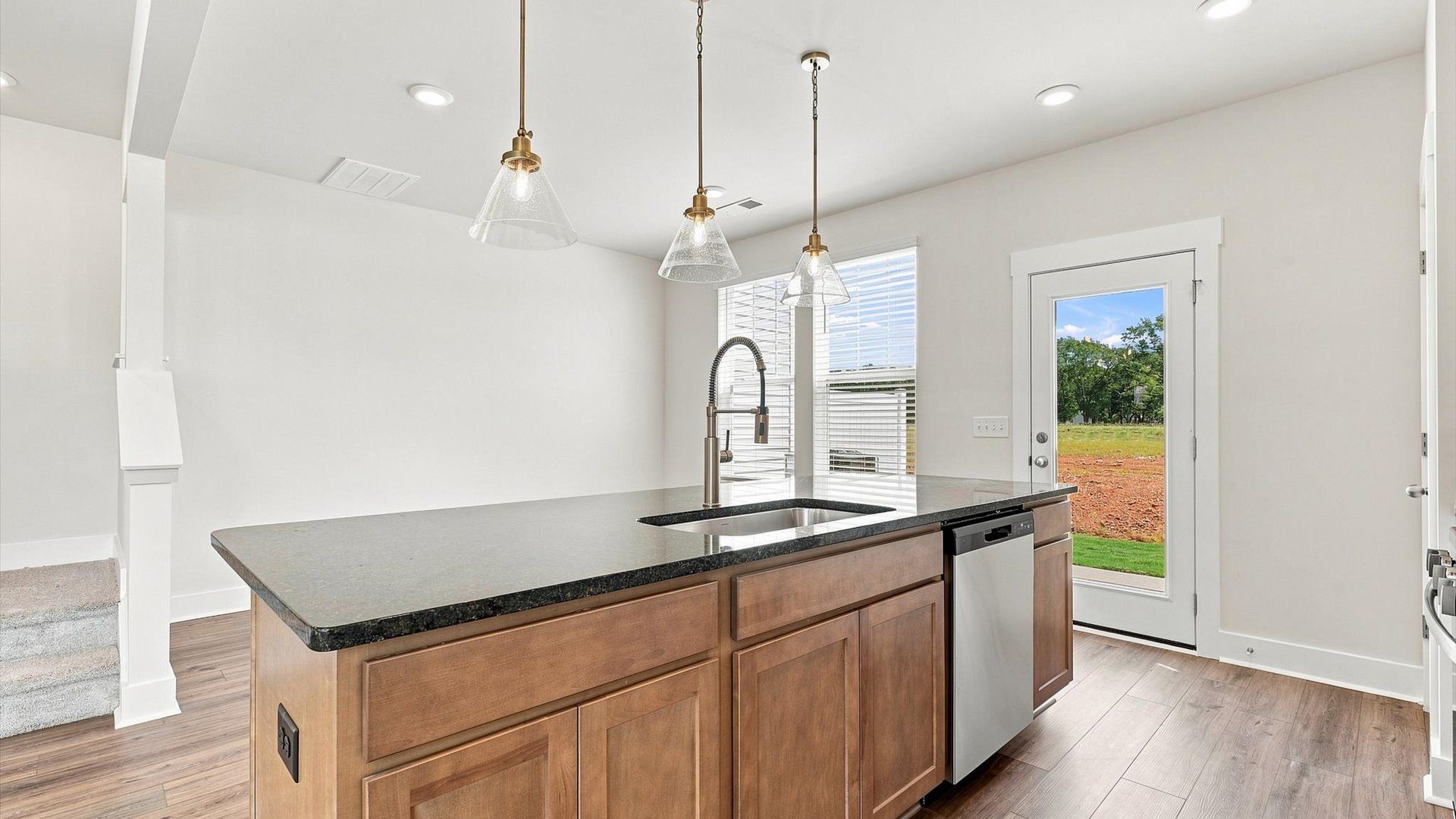 Vibrant and open kitchen centered around a large island with elegant pendant lighting above at Saluda Crossing