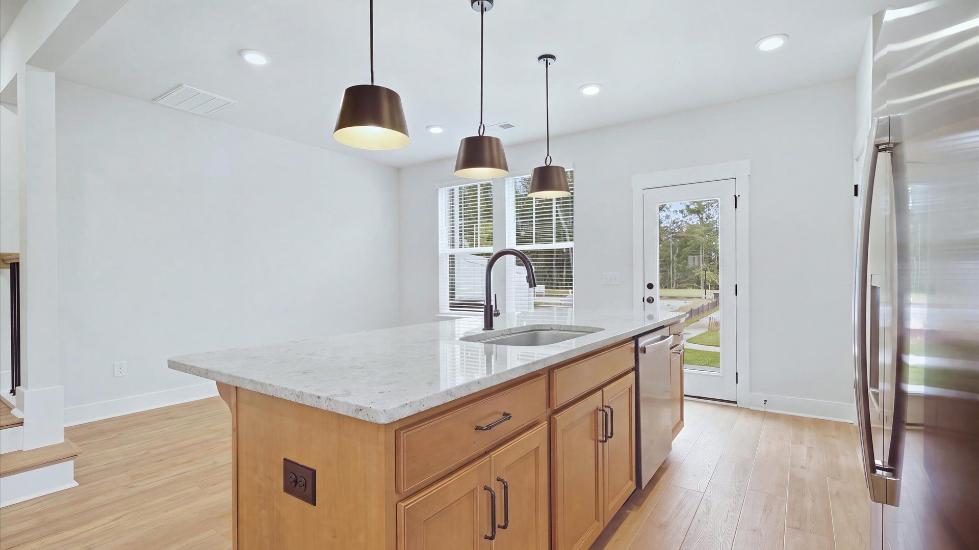 Highly skilled kitchen design includes a 9-foot island, quartz countertops, and stylish pendant fixtures