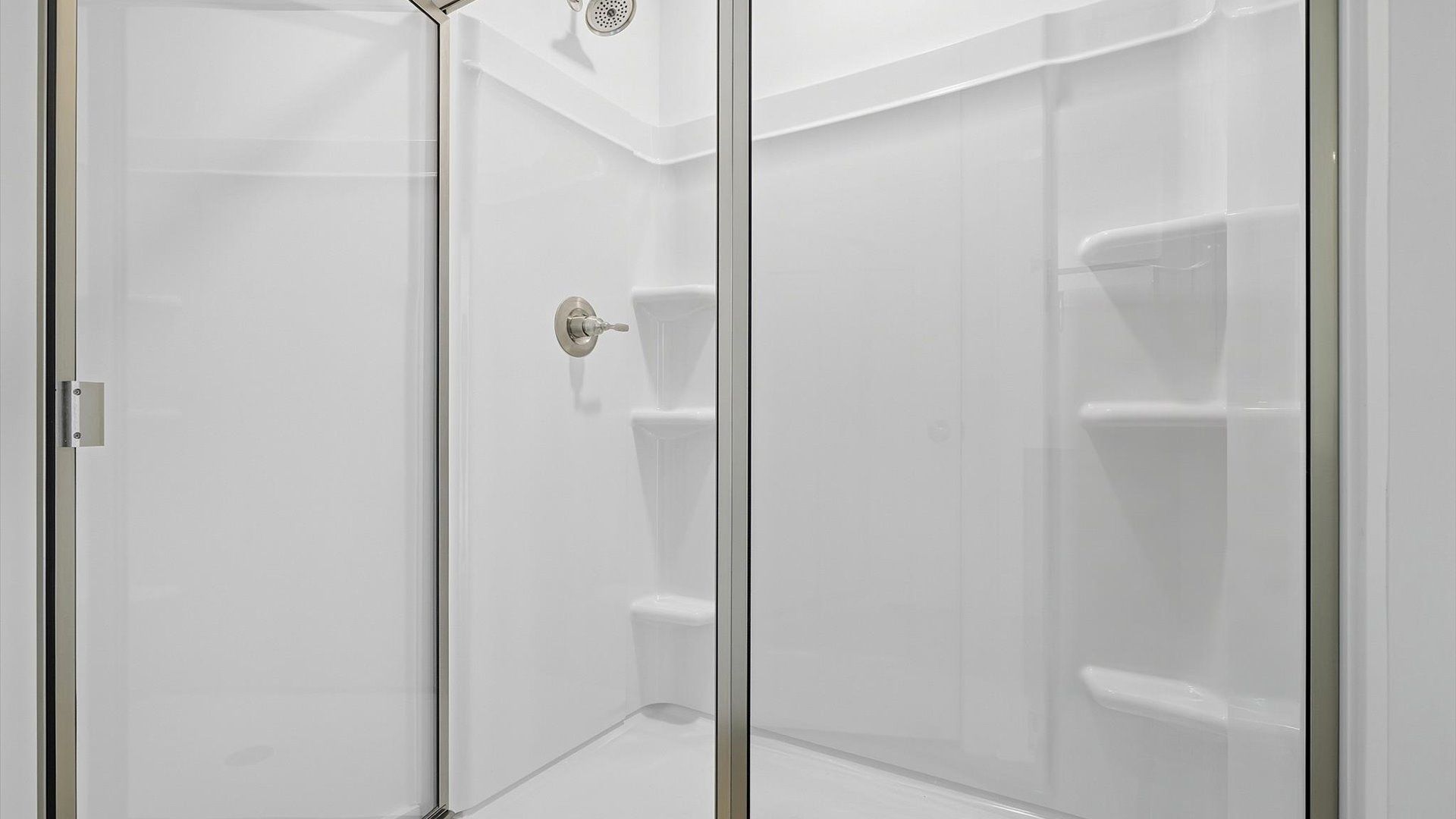Spacious and modern primary bathroom with walk-in shower and good lighting by DRB Homes