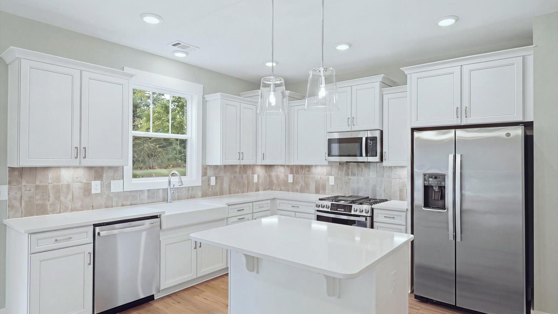 Highly skilled craftsmanship shines in this modern kitchen with pendant lighting and a central island focal point by DRB