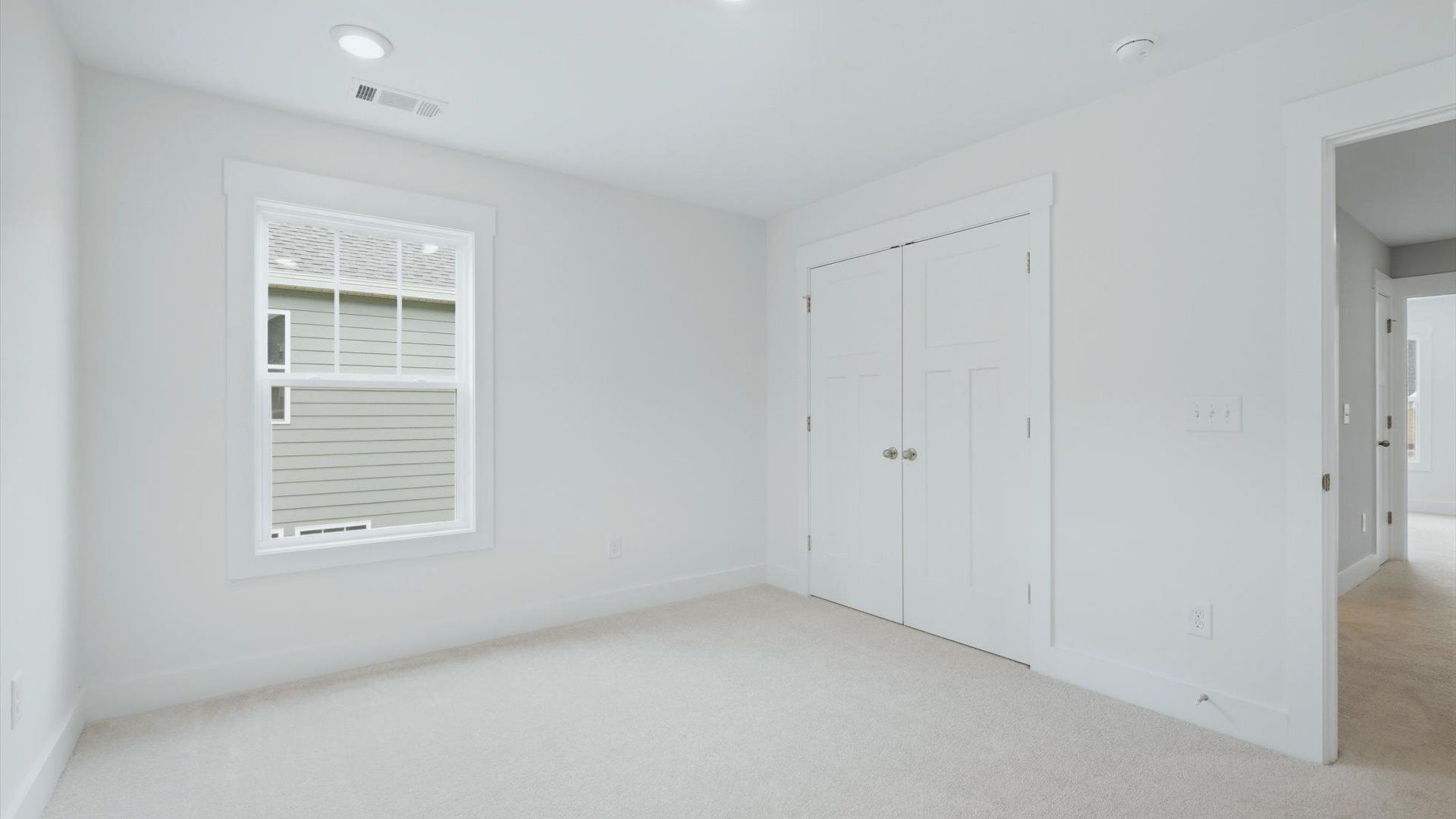 Highly functional bedroom with a large window, carpeted flooring, and tasteful finishes throughout
