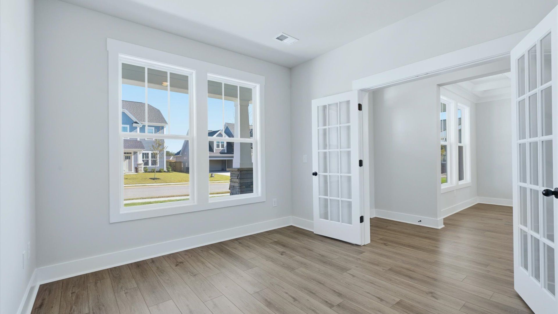 Vibrant natural light and tasteful design define this French door study near the front of the home