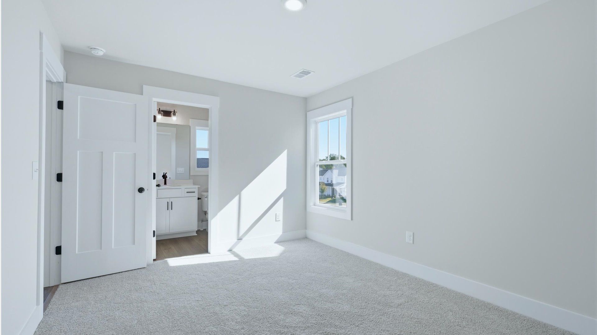 Tasteful bedroom with plush carpet, an en suite bathroom, and large windows for abundant natural light in Anderson, SC