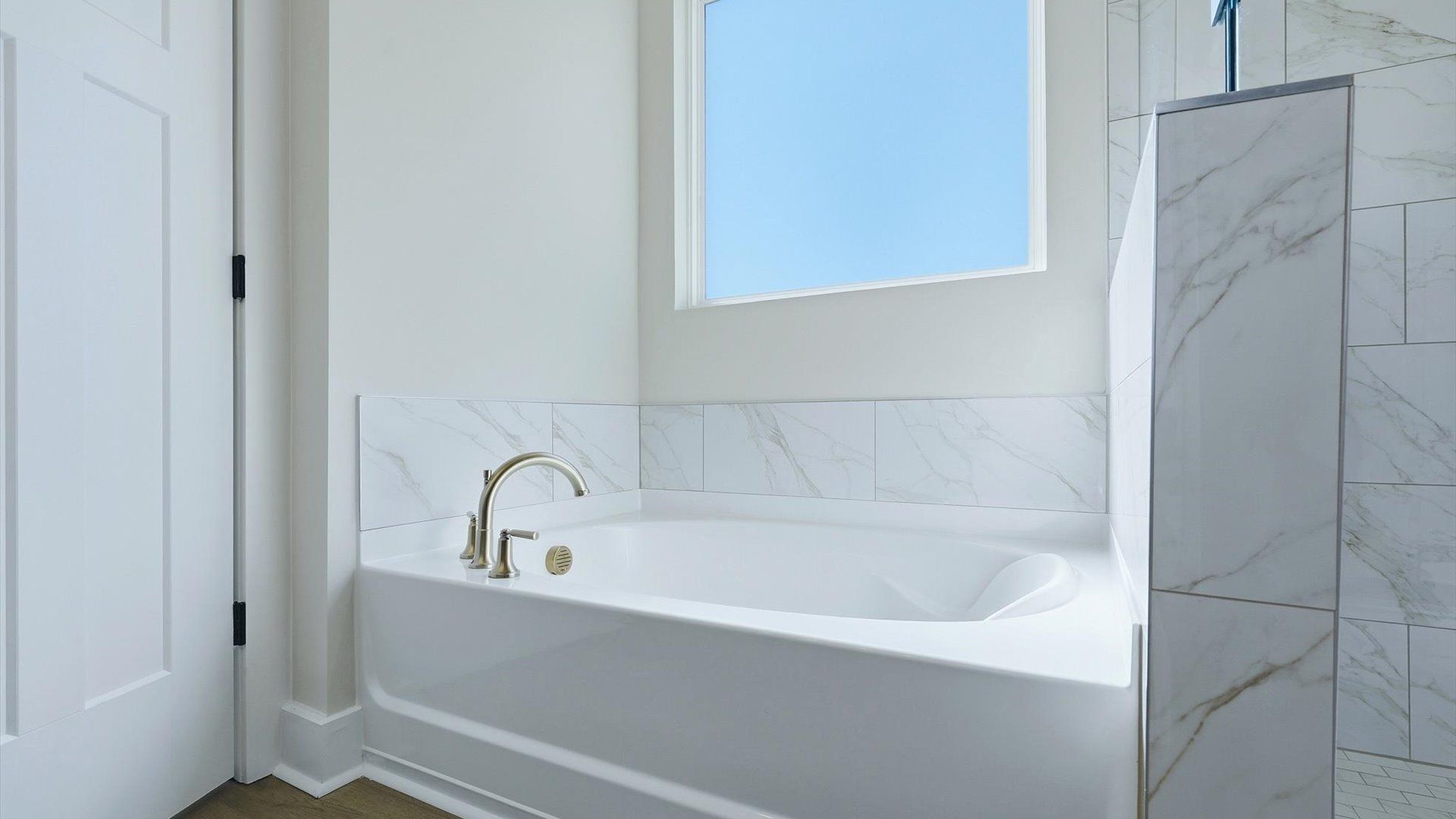 Memorable mornings begin in this elegant primary bathroom with a soaking tub and natural light