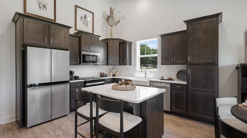 DRB Homes' Magnolia Park with two story ceiling kitchen with dark wooden cabinetry and kitchen island in Woodruff, SC