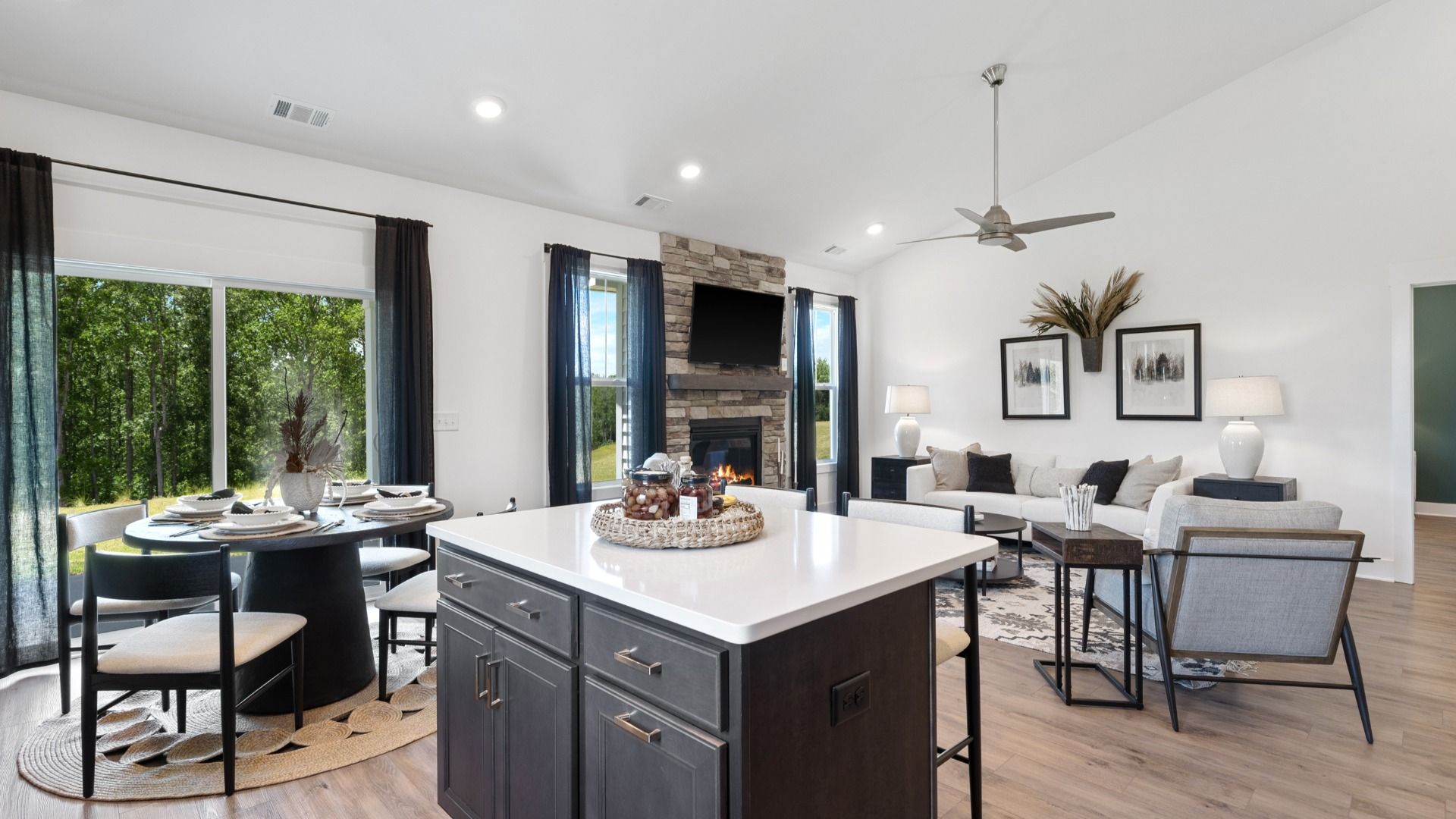 Dark wooden cabinetry kitchen with modern farmhouse decor, two story ceilings & kitchen island at Magnolia Park by DRB Homes