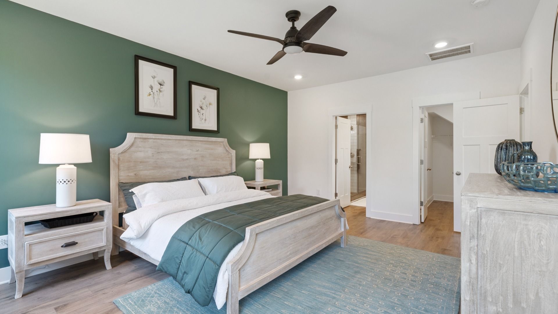 DRB Homes' Magnolia Park Primary Suite with hardwood flooring and ceiling fan with calming green accent wall in Woodruff, SC
