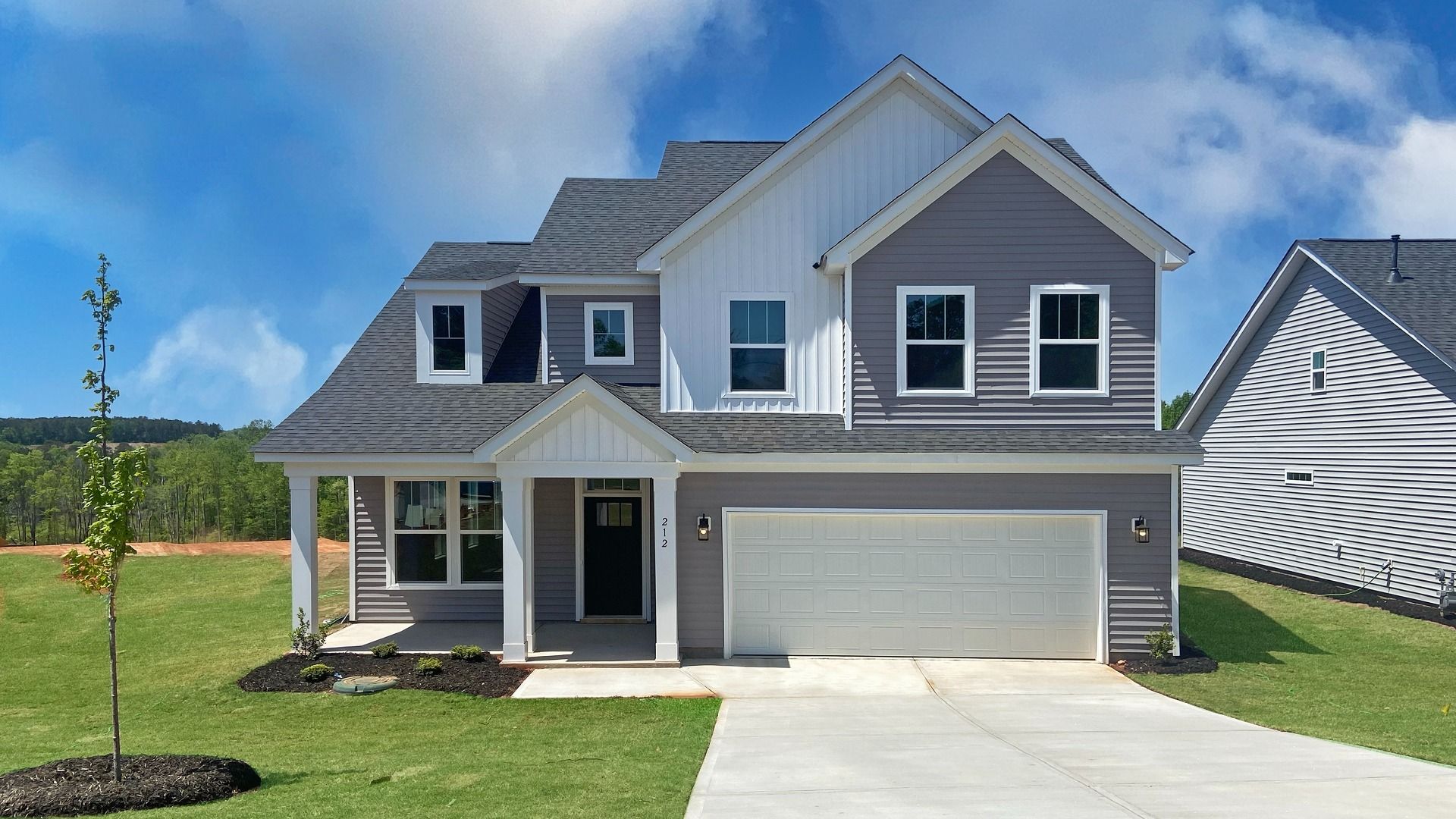 Cameron floorplan with two car garage and covered front porch with gray and white exterior siding at Woodglen by DRB Homes