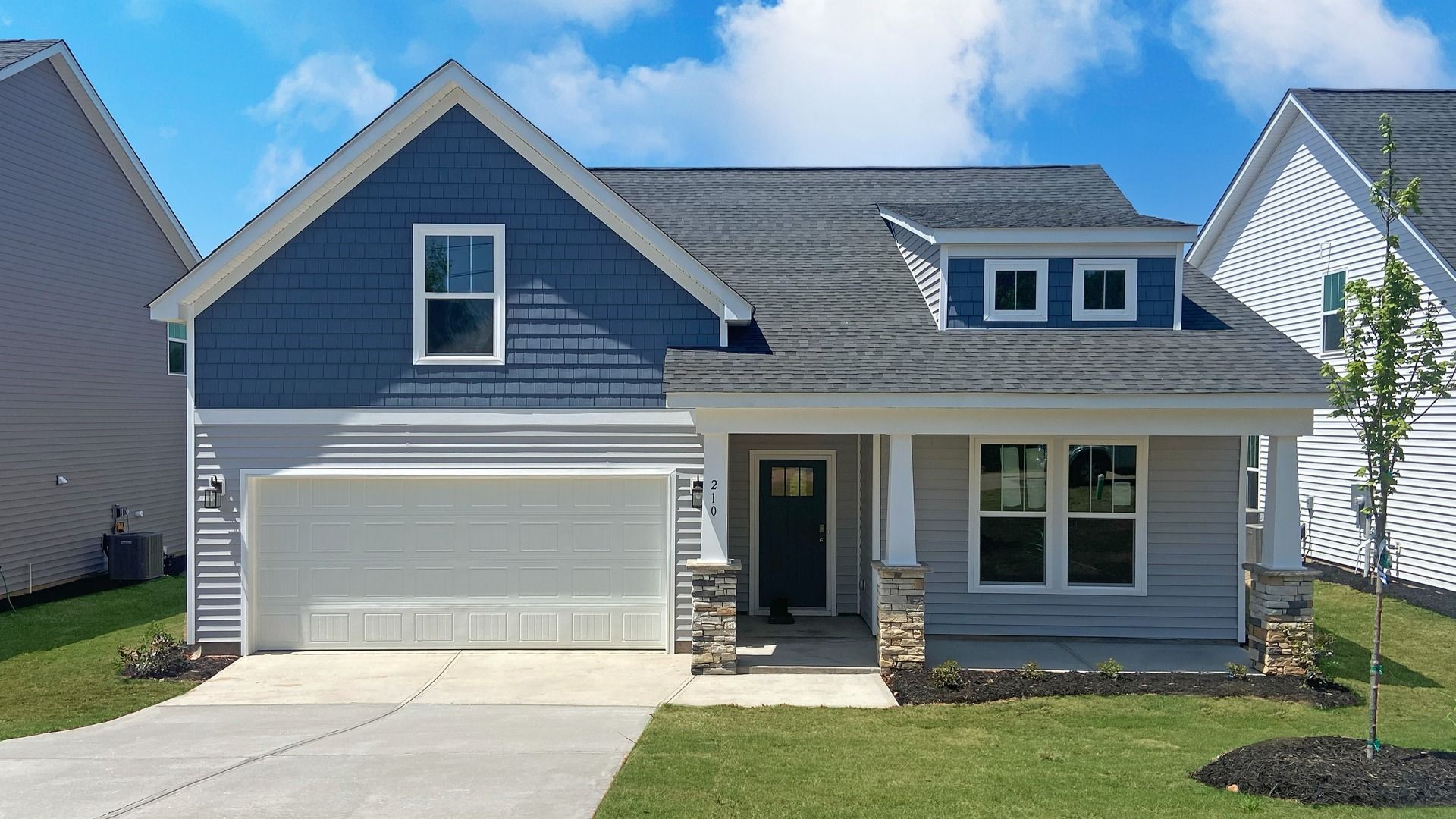 New blue and gray exterior Parker by DRB Homes with stone columns and two car garage at Walnut Ridge in Inman, SC