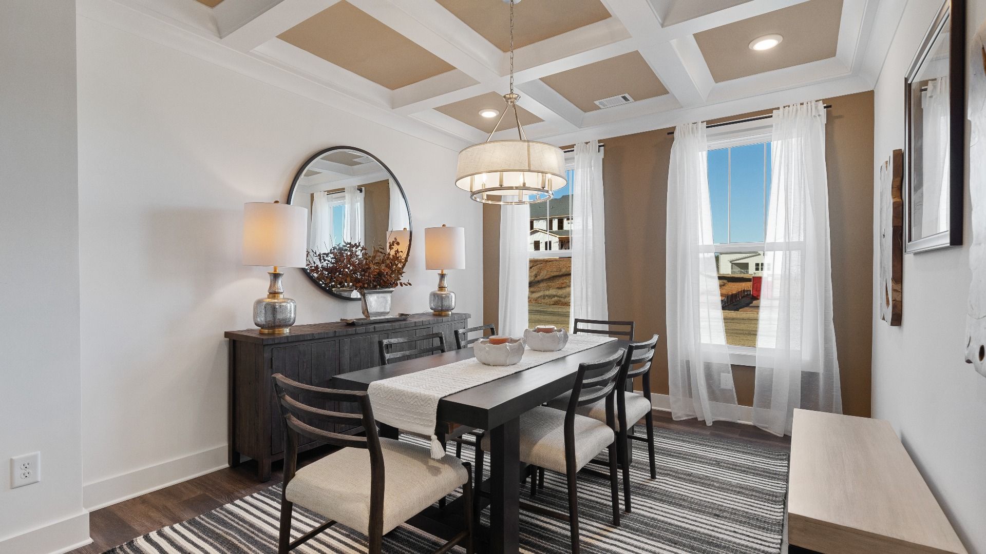 Stunning coffered ceiling dining room with chandelier, large windows, and hardwood flooring at Walnut Ridge by DRB Homes