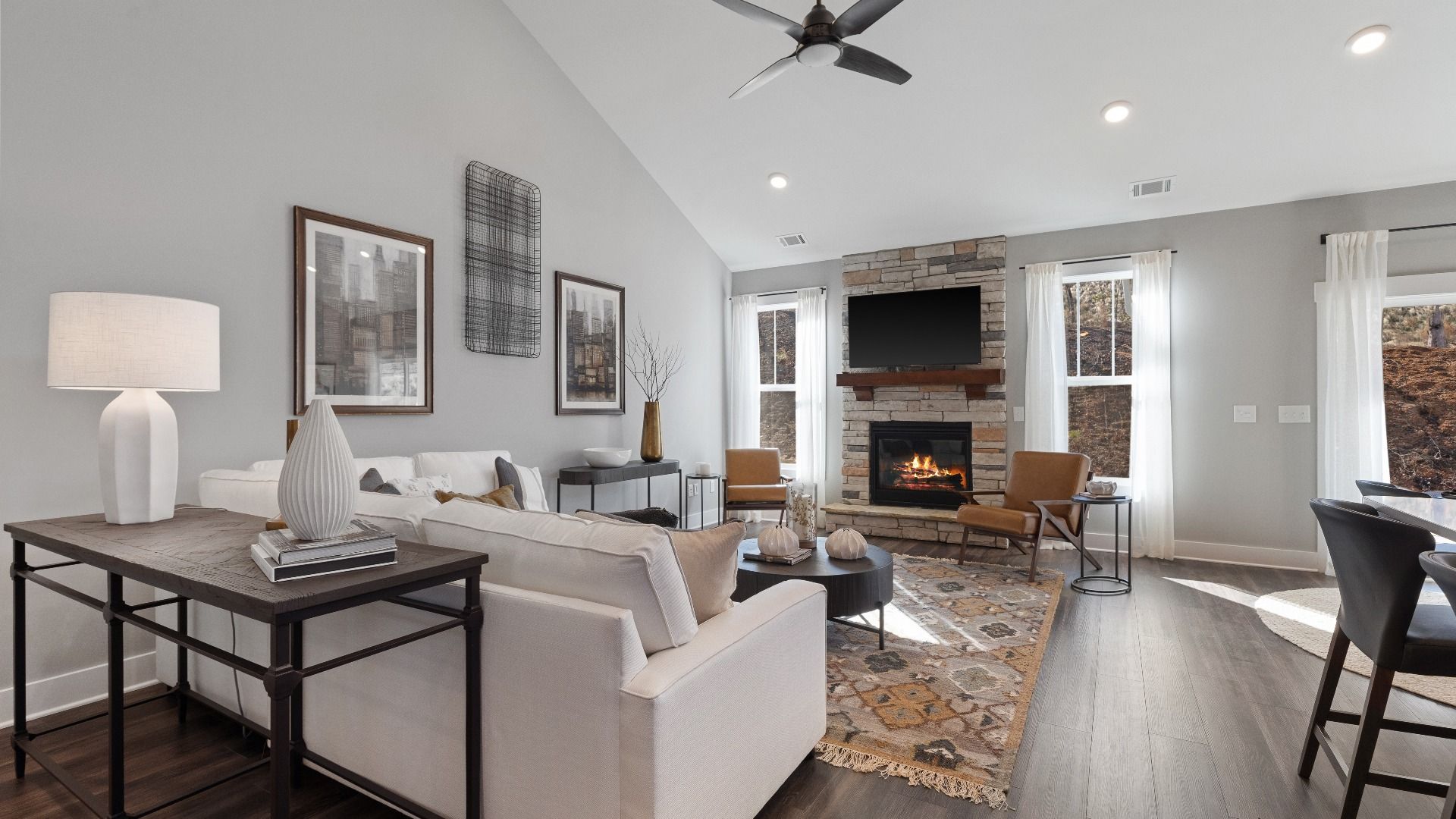 Two story ceiling, open concept family room with hardwood flooring, ceiling fan, and stone detailed fireplace in Inman, SC