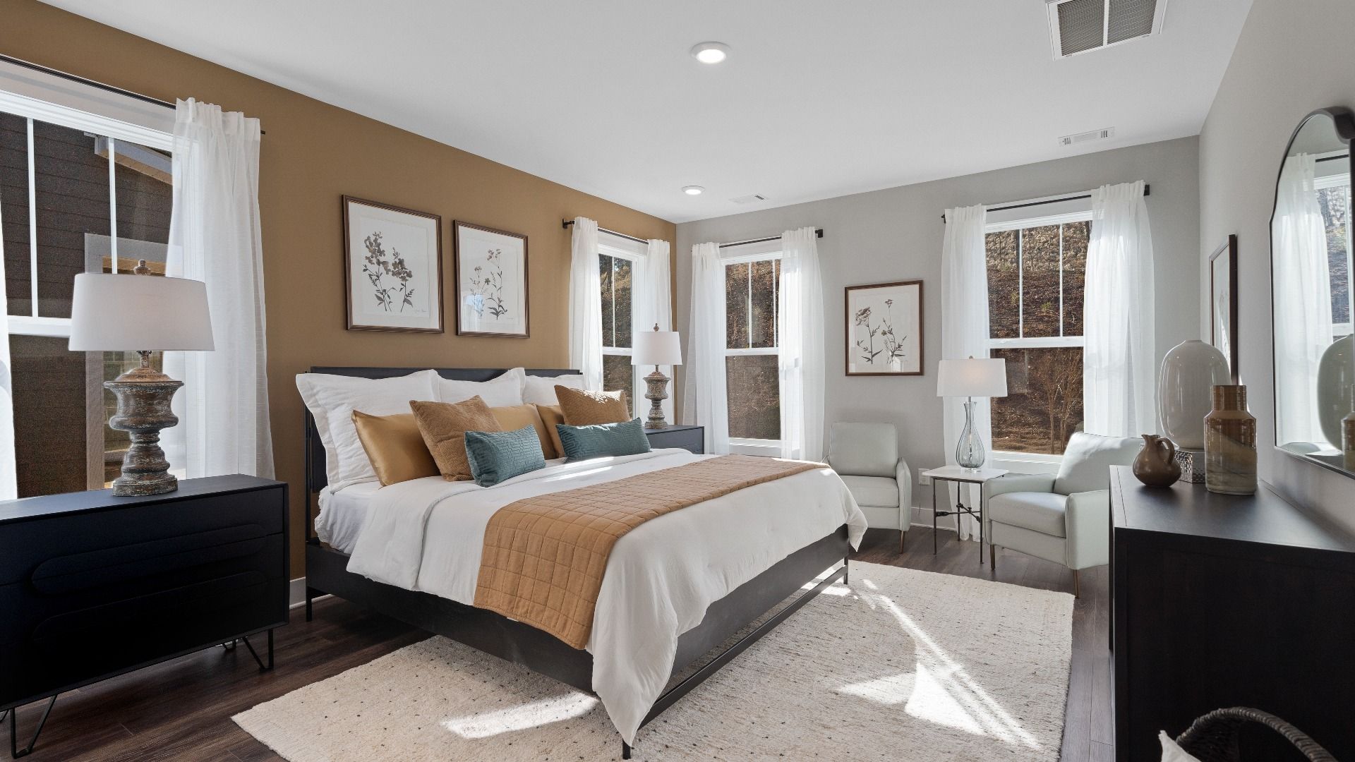 Primary suite with hardwood flooring, large windows, and accent wall at Walnut Ridge by DRB Homes in Inman, SC