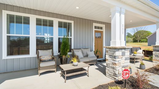Covered, spacious front porch with stone columns and large windows at Wells Crossing by DRB Homes in Seneca, SC