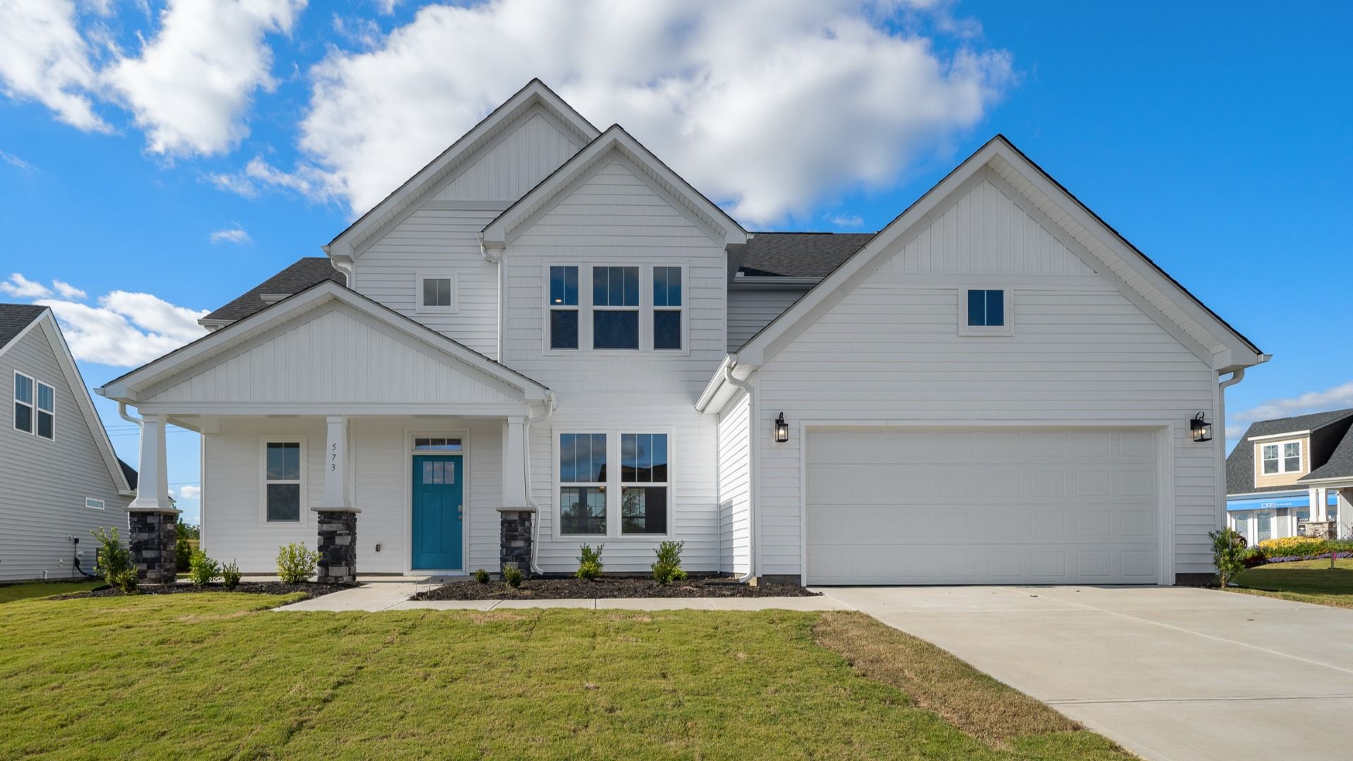 Arlington floorplan with bright white exterior, stone columns, blue door, and two car garage at Wells Crossing in Seneca, SC