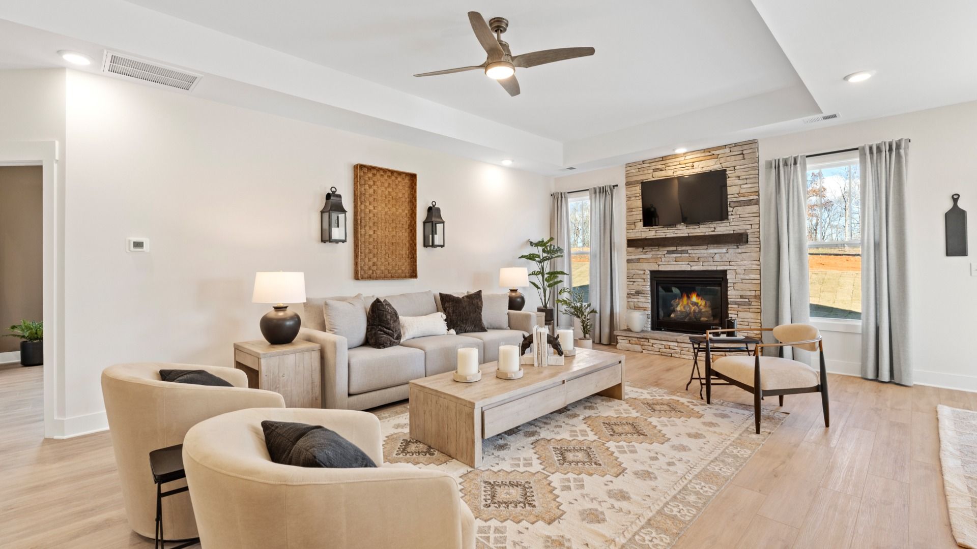 Cozy, inviting family room with stone fireplace, vaulted ceiling, overhead fan, and LVP flooring at Fox Hollow by DRB Homes